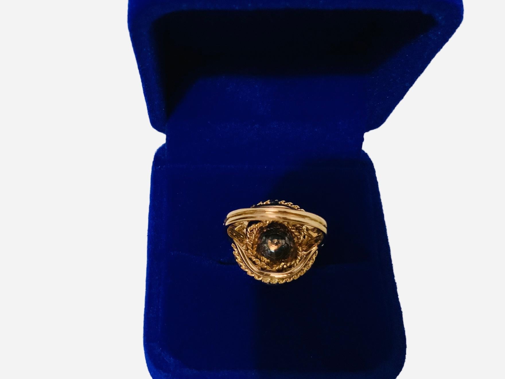 This is a 18K Gold Flower Design Cocktail Ring. It is a dome ring with four different levels. The lower level at the bottom is made of a gold rope. The third one is made of a gold swag followed by double ropes that are braided. Finally the first