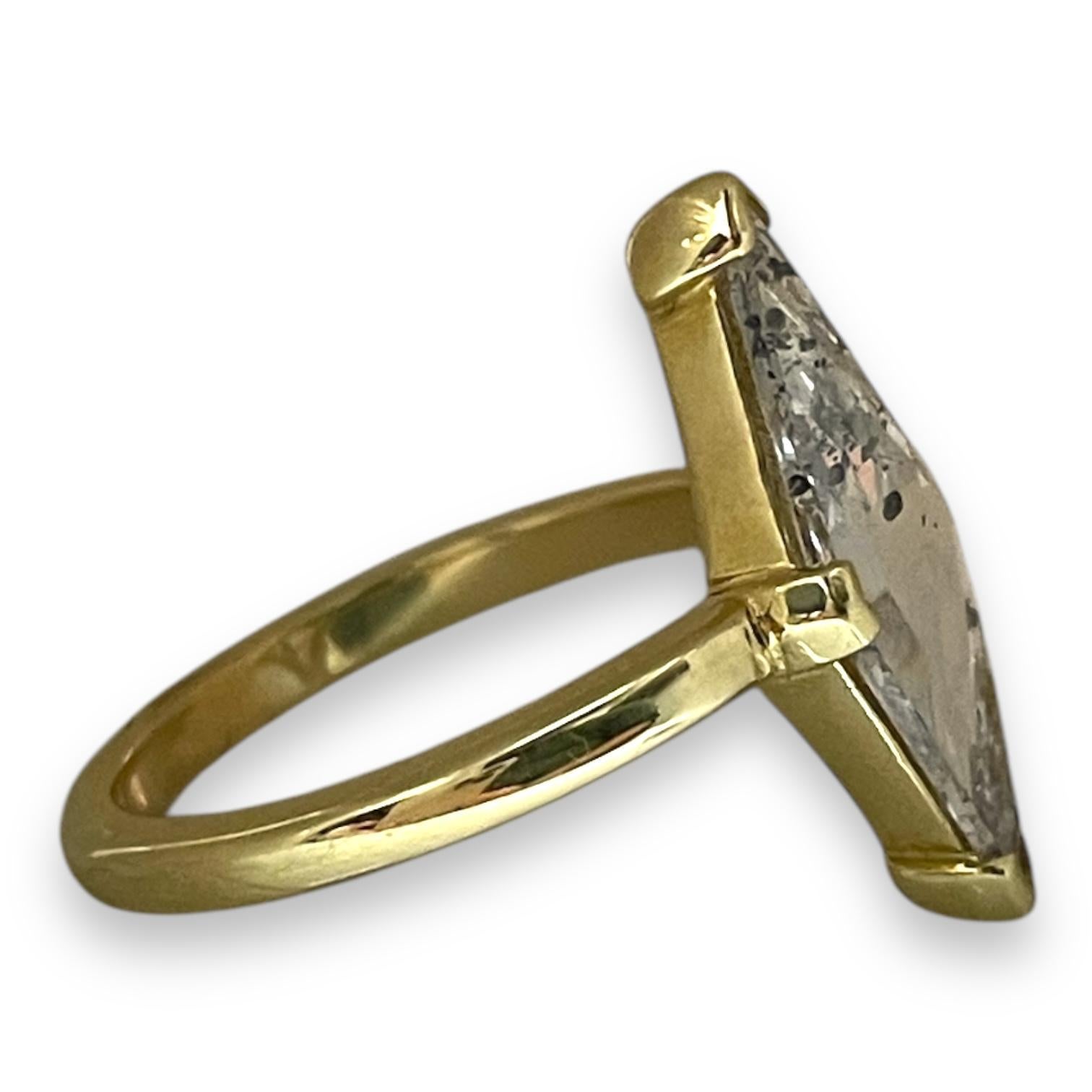 Showcasing a striking design, this ring features a uniquely cut diamond set in a sleek gold band. The elongated, angular shape of the diamond creates a captivating focal point, while the gold setting enhances its brilliance. A bold statement piece