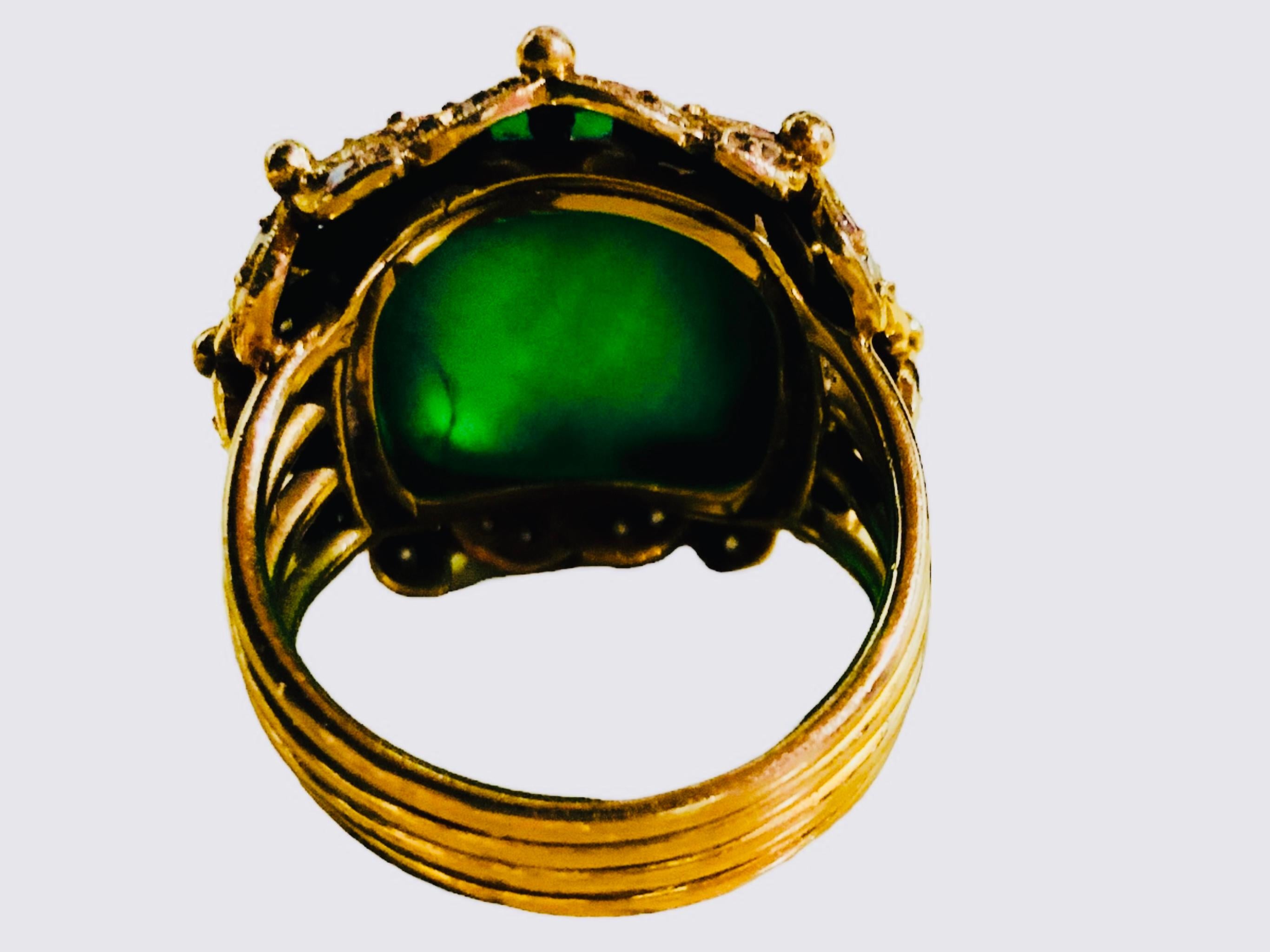This is an 18K yellow gold, green emerald color crystal and diamonds ring. It depicts a high dome/bullet shaped semi-transparent green crystal measuring 13.5 x 13.5 x 9.5mm on gold bezel setting. Its base surrounded by a wreath made of four petals