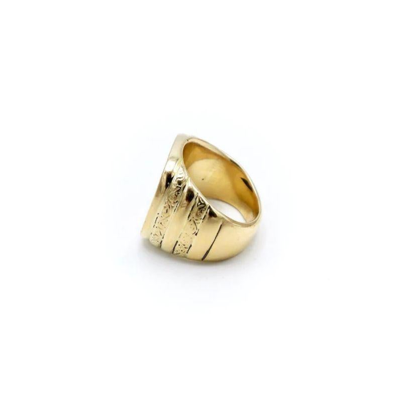 This elegant and bold 18 karat gold ring features elaborate hand-engraved and carved rhythmic curling motifs that create a symmetrical pattern. The decorative elements cover the flat top of the band and continue over to the sides in a more