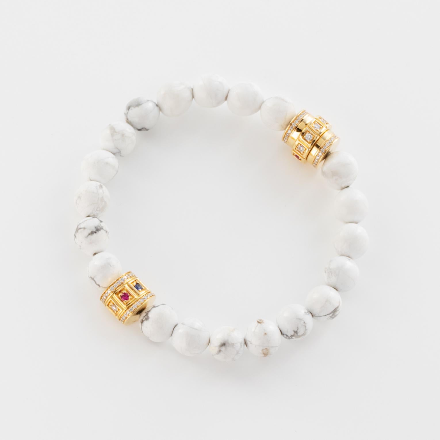 18k Howlite Beaded Code Bracelet features large round Howlite stone beads with two 18k Yellow Gold Code Dials, containing White Diamonds, Rubies, Emeralds, and Blue Sapphires. 
Rolls Onto the Wrist 
From the James Banks Code Collection 

