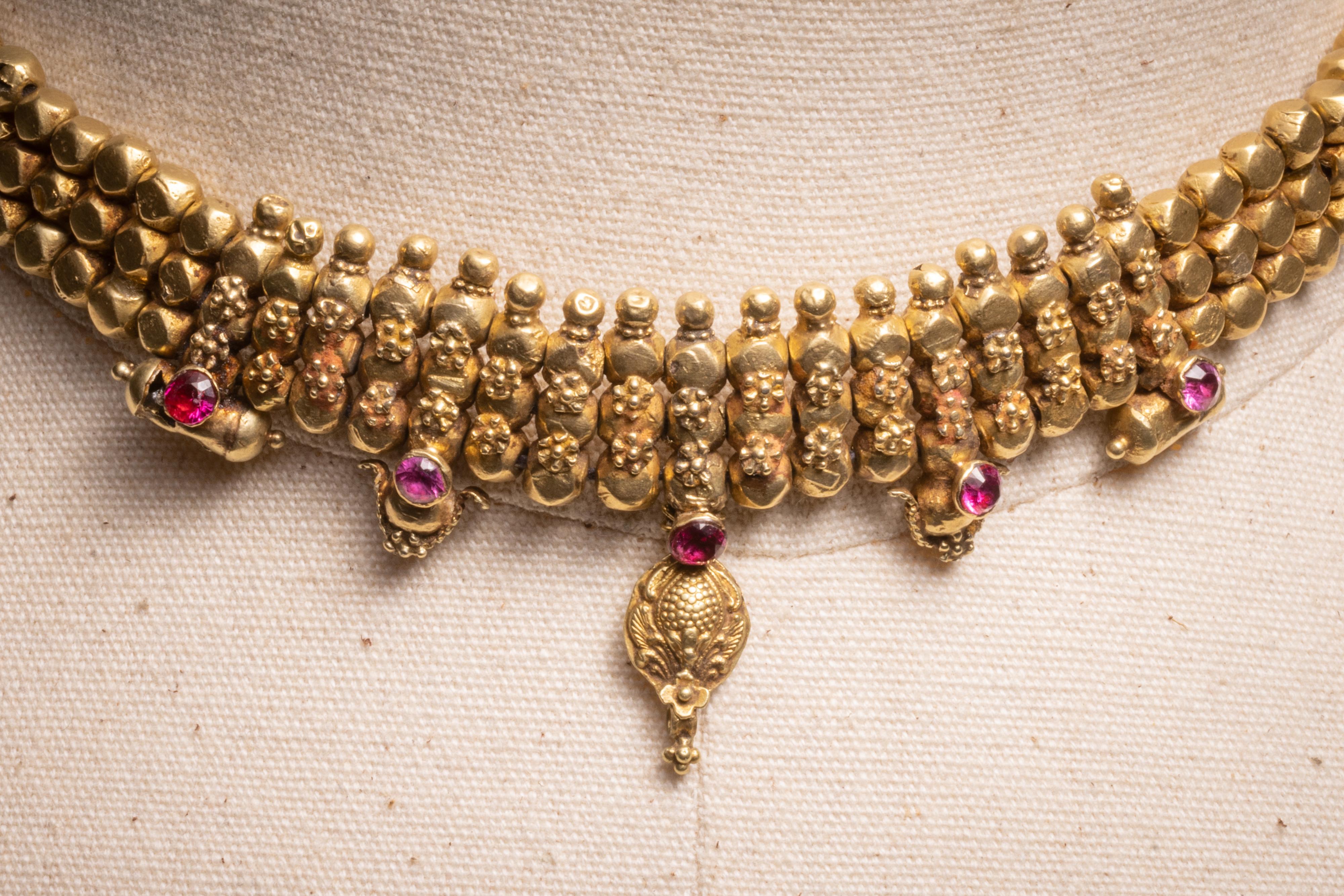 A  traditional 18K gold Indian choker necklace with an adjustable bolero clasp.  Fine tooling and granulation work and pink spinel.  Dates to the 1940's.  The bolero clasp allows it to vary in length.  The shortest being 11