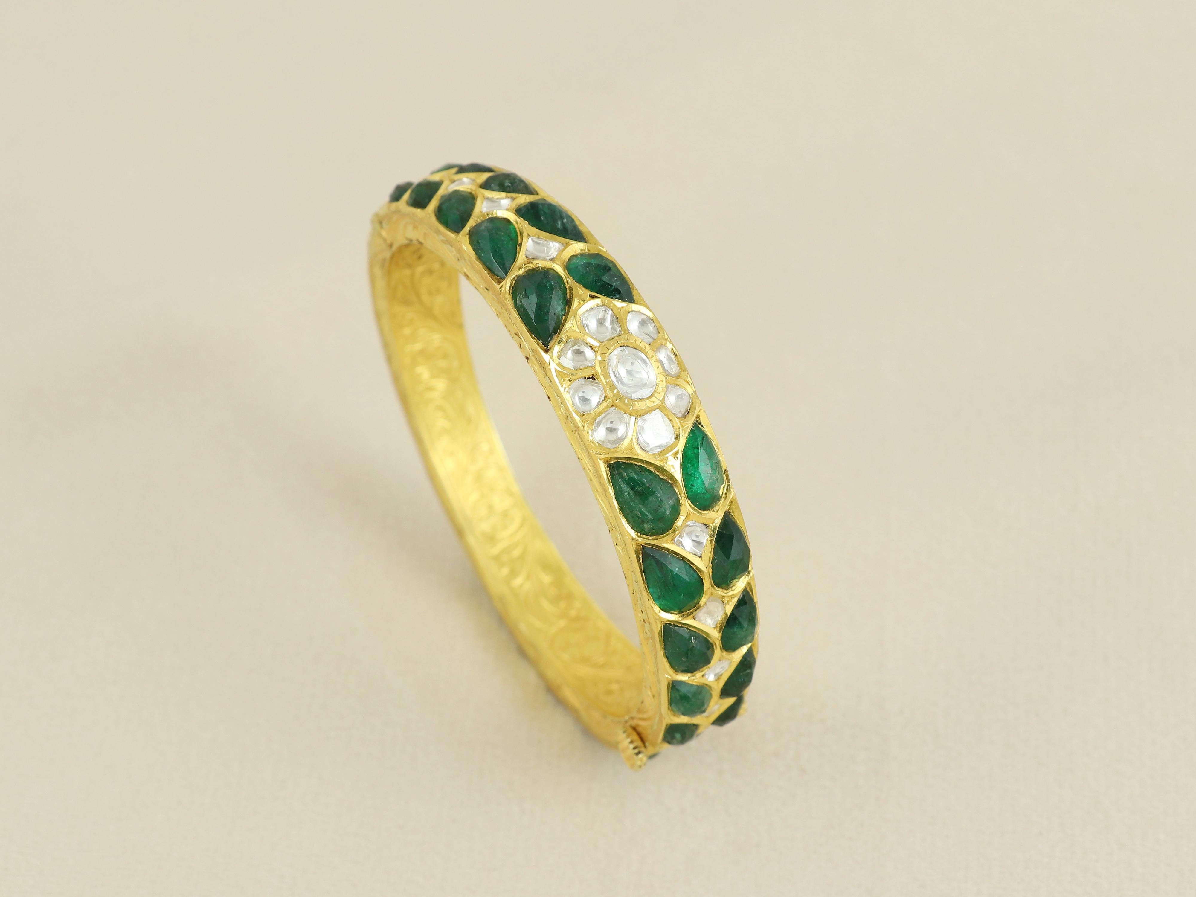 Una vera e propria celebrazione dell'artigianato regale, questo braccialetto in oro 18 carati è un'opera d'arte della gioielleria Mughal. Incastonato con vivaci smeraldi naturali, ciascuno meticolosamente tagliato in gemme sfaccettate a forma di