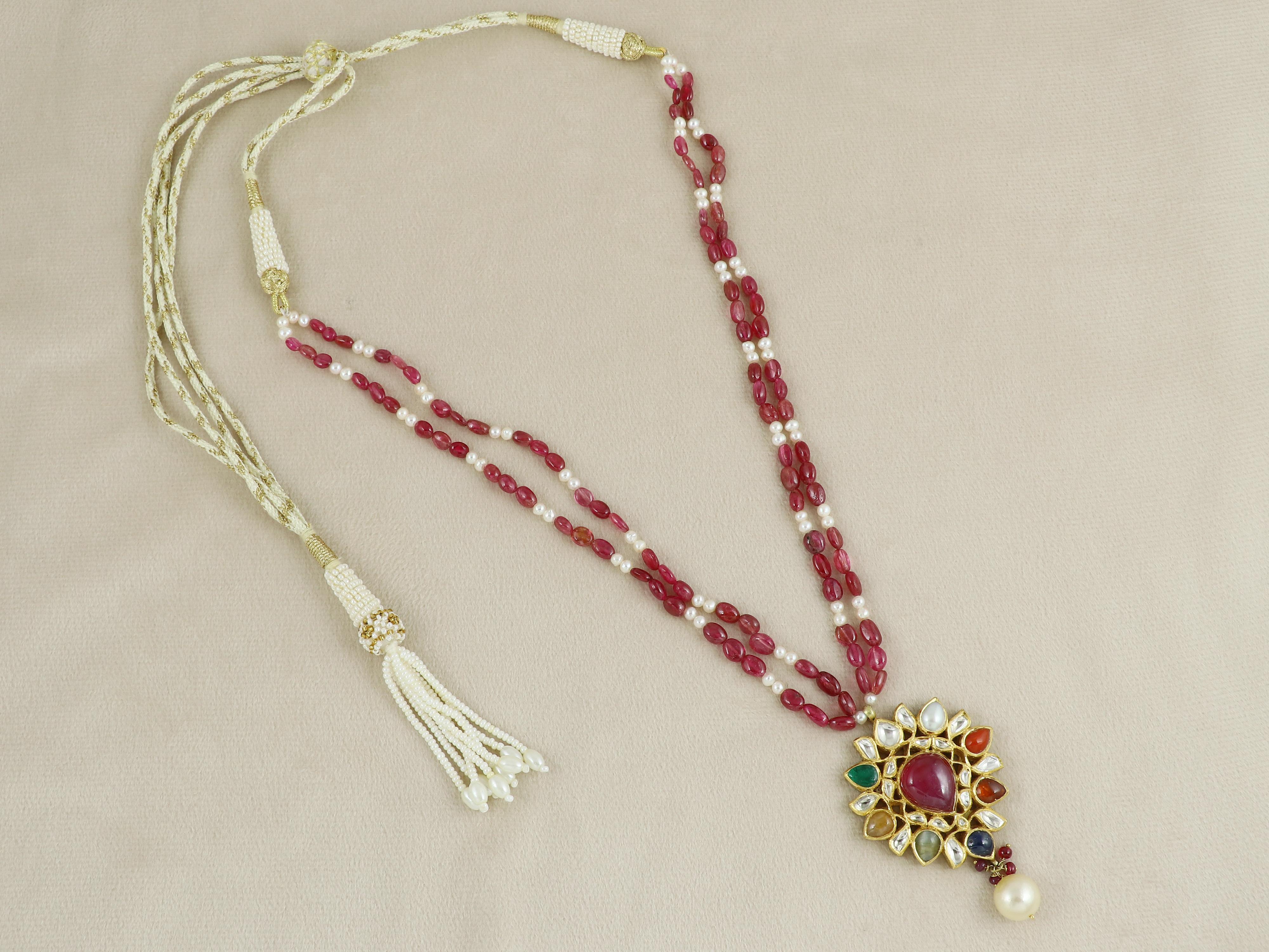 Presenta un raffinato pezzo di eleganza indiana: questo pendente Navratan in oro 18 carati è un'espressione compatta ma potente della ricchezza culturale e dell'armonia spirituale. Incastonato con le nove gemme sacre del Navratan - ognuna delle