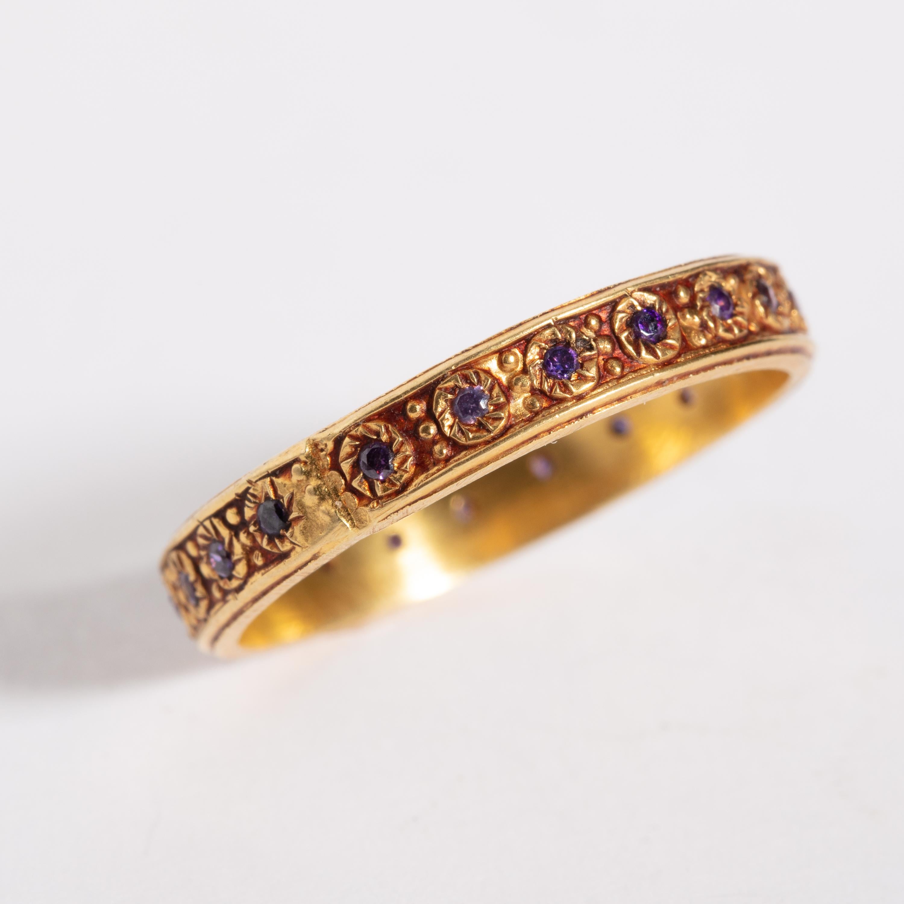 An 18K gold infinity band with fine granulation work set with faceted amethyst stones.  Ring size is 8.5  Late 1900's