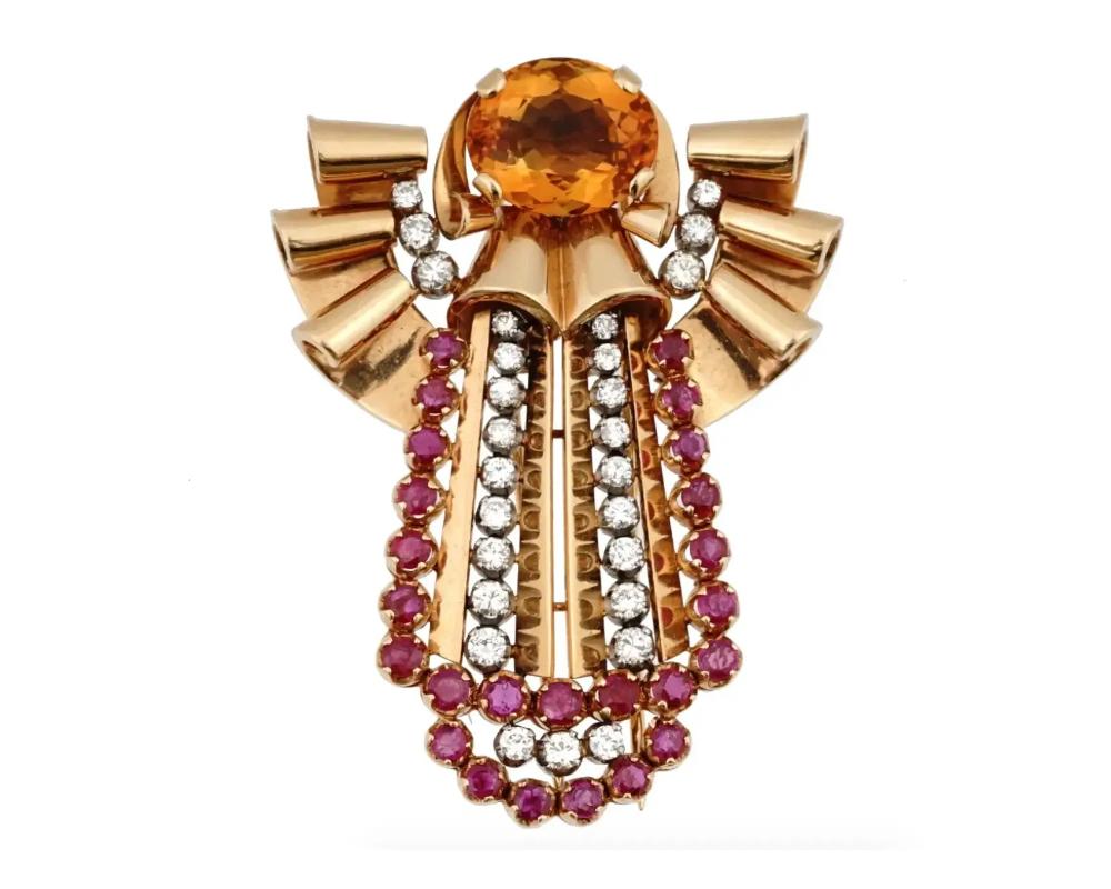 An 18K Yellow gold figural brooch. The brooch is made in a ribbon design, and encrusted with a large Citrine stone. The ware is encrusted with Ruby stones and Diamonds. Weight 35.75 grams. Vintage and Modern Jewelry Wares and Accessories For