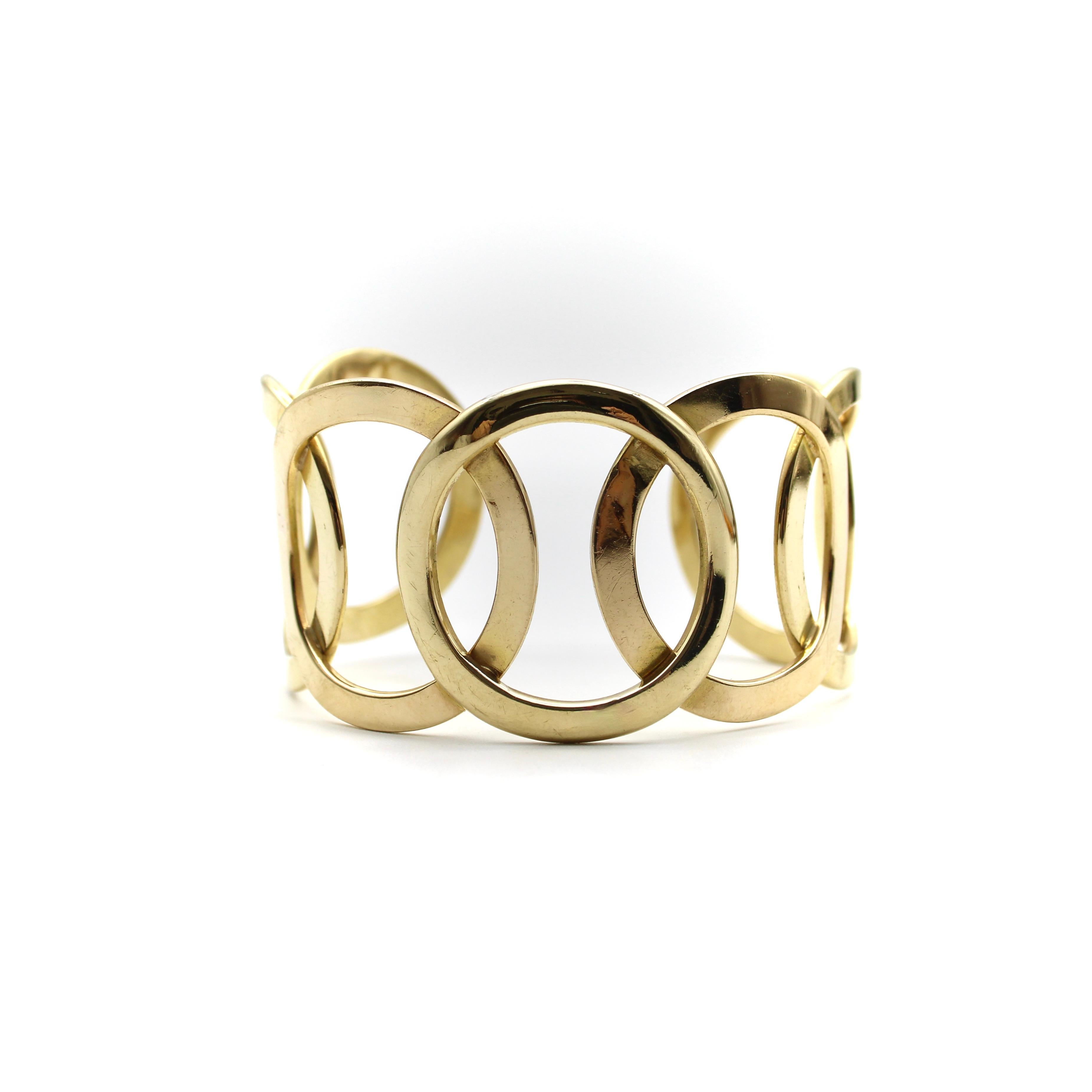 Dieses fabelhafte Manschettenarmband erinnert an die olympischen Ringe und besteht aus einem zentralen Kreis, in dem sich die Kreise auf beiden Seiten spiegeln. Dieses modernistische Armband aus den 1970er-Jahren nutzt den negativen Raum, um eine