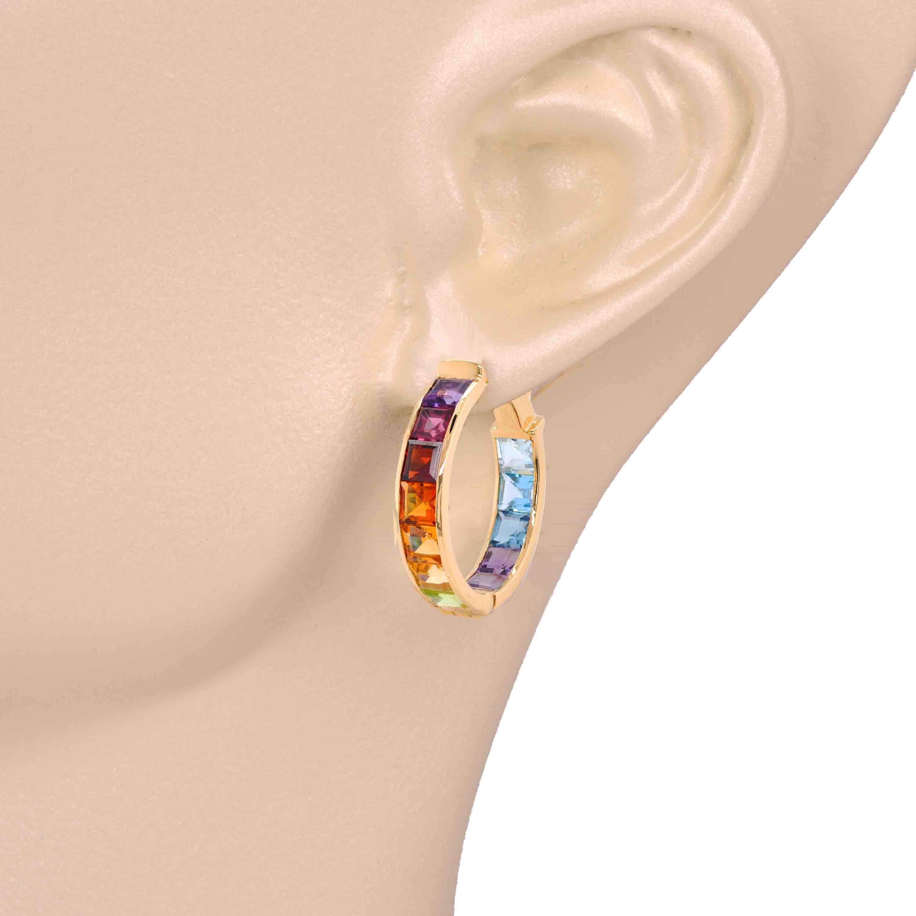 Presenting the 18 karat yellow gold multi-color rainbow channel set hoop earrings – a blend of contemporary elegance with playful charm. These earrings feature a sleek hoop design adorned with carefully arranged multicolored gemstones set securely