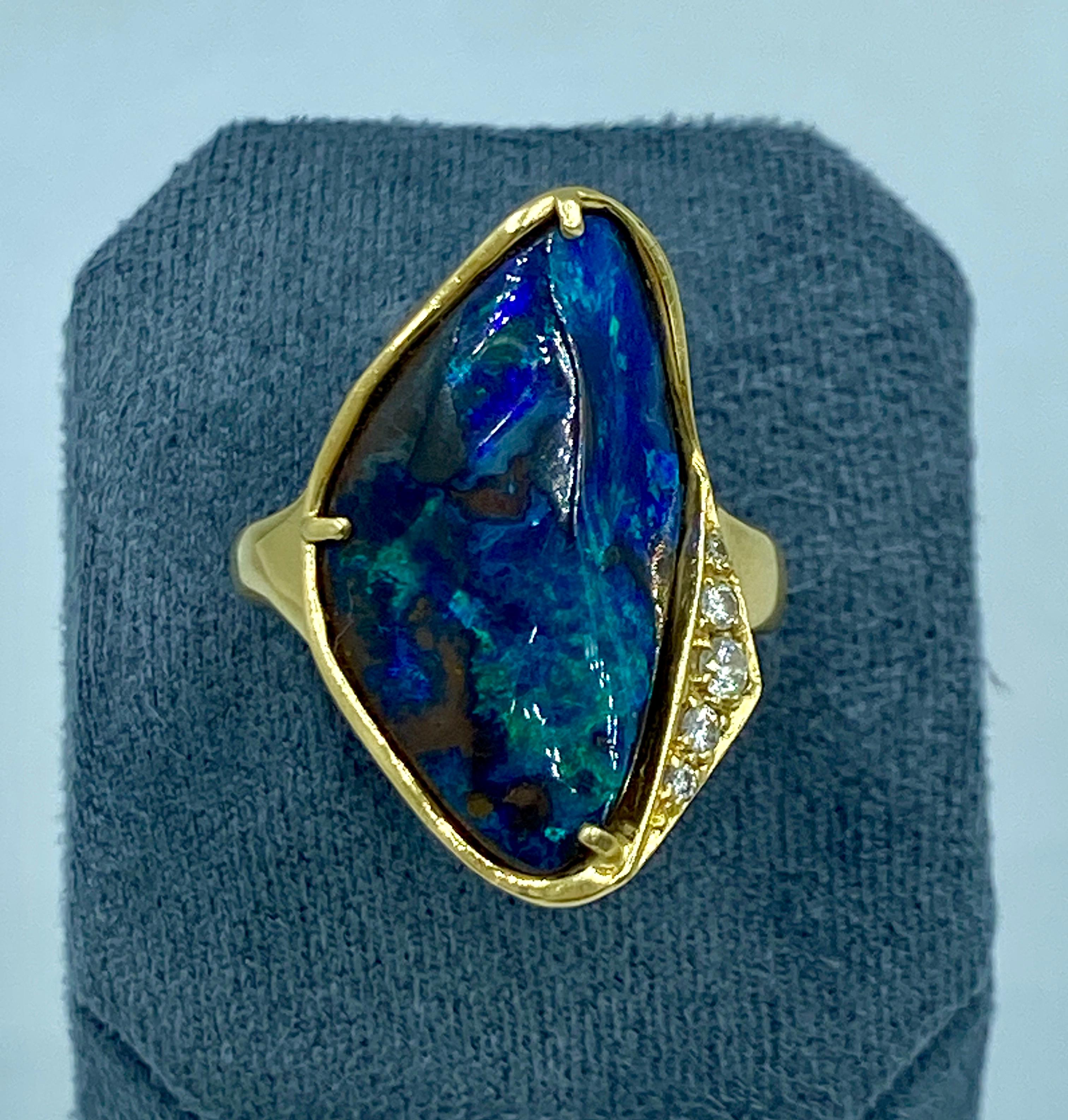 Este llamativo anillo de ópalo negro de los años 70 está engastado en oro de 18 quilates y adornado con 5 diamantes de talla redonda que suman aproximadamente 0,15 quilates.