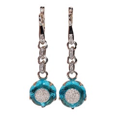 Boucle d
oreille pendante en or 18 carats ornée de diamants naturels et de topazes bleues