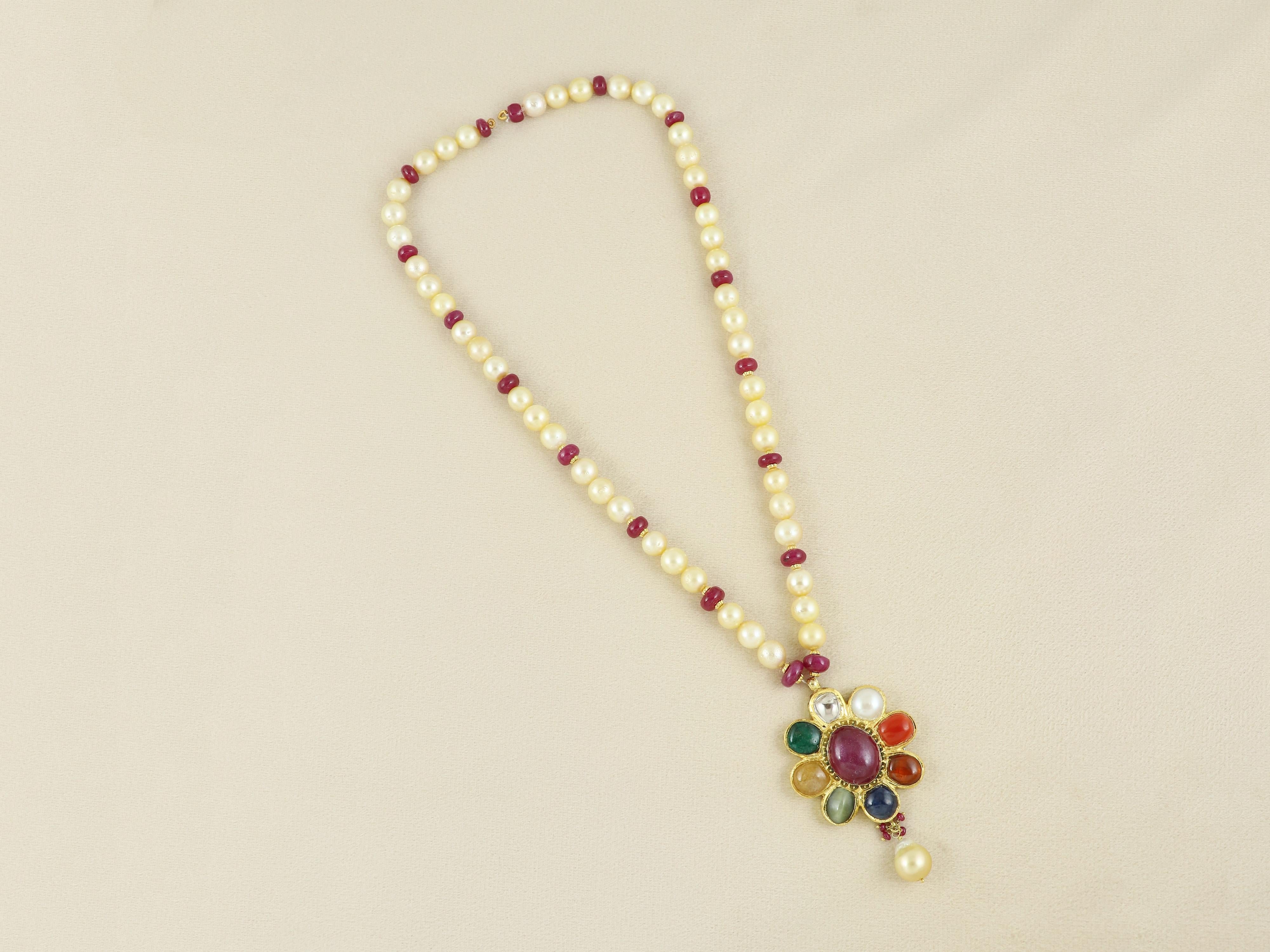 Realizzato a mano in oro 18 carati da artigiani di Jaipur, questo squisito ciondolo Navratna è una lussuosa espressione di armonia cosmica. Con nove pietre sacre incastonate - rubino di Bangkok (riempito di vetro), diamante naturale polki, smeraldo,