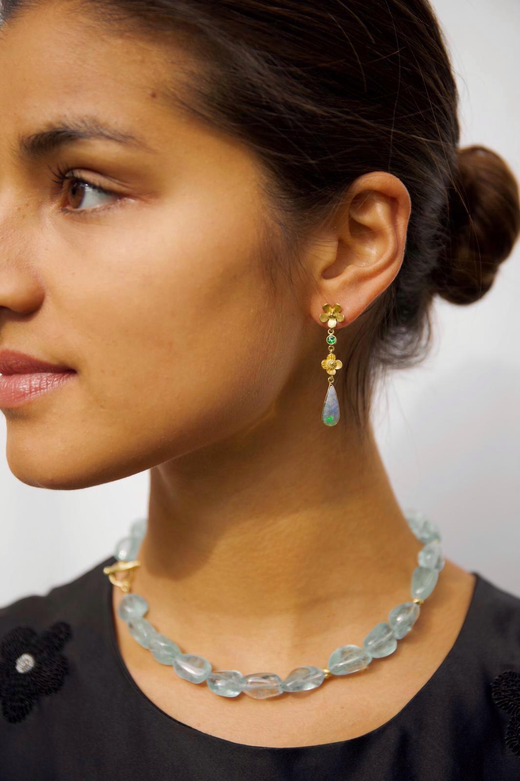 A lovely handmade and one-of-a-kind pair of asymmetrical 18k gold earrings with boulder opals and lush green peridots suspended from 18k gold flowers. The asymmetry accentuates the beauty and uniqueness of the opals. A feminine and lightweight piece