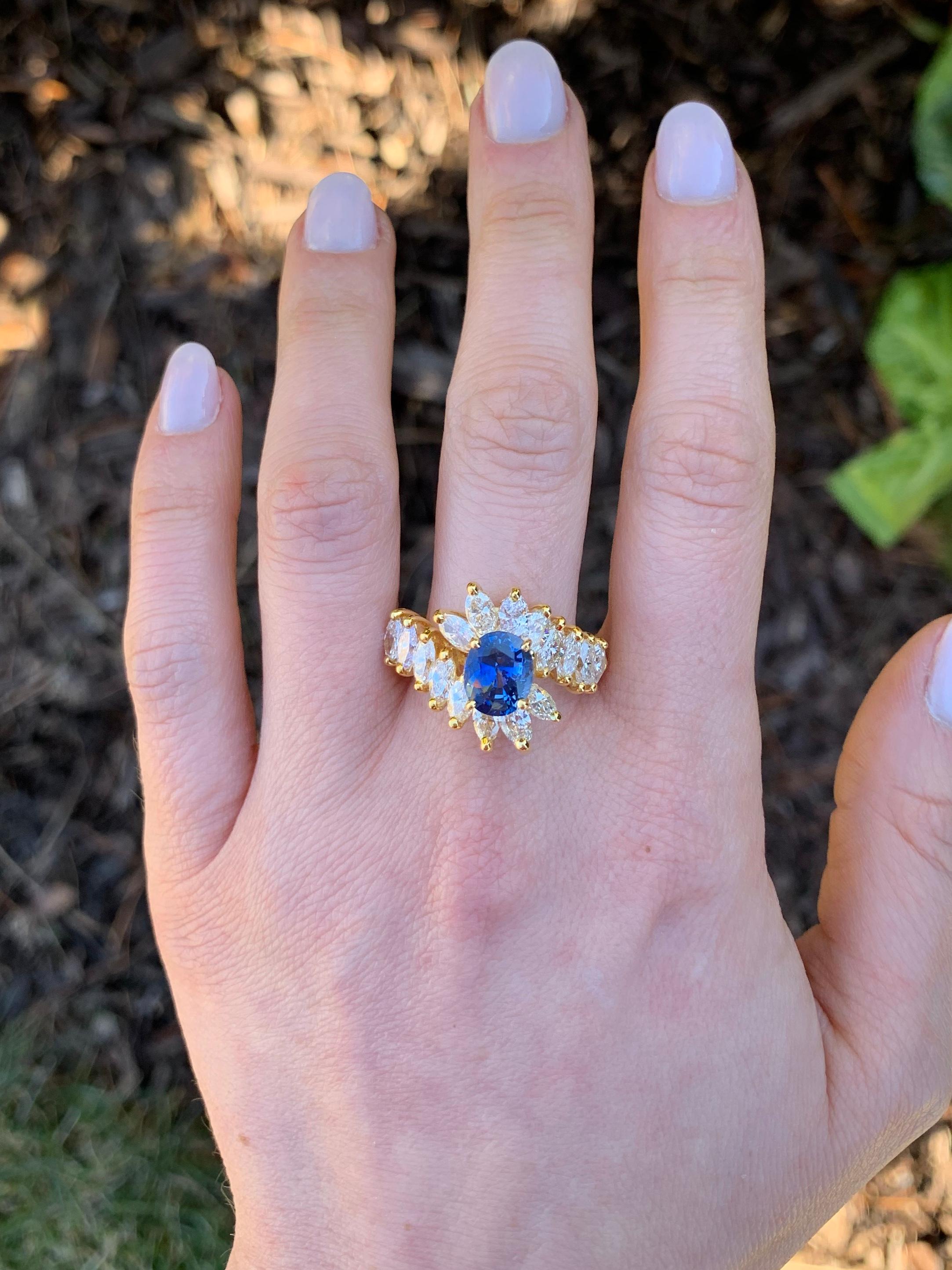 A beautifully saturated 2.09 carat oval blue sapphire is surrounded by sixteen prong-set marquise cut diamonds at 2.55 carats total weight. Diamonds are approximately G color, VS2 clarity. Oval blue sapphire has medium transparency and a beautiful