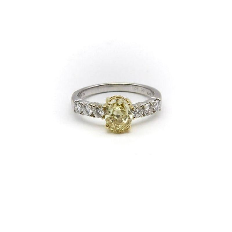 This beautiful 18k gold ring features a central oval yellow diamond surrounded by six sparkling white diamonds. The contrast is lovely: the yellow diamond is held in 18k yellow gold, which brings out the yellow color of the diamond, while the white