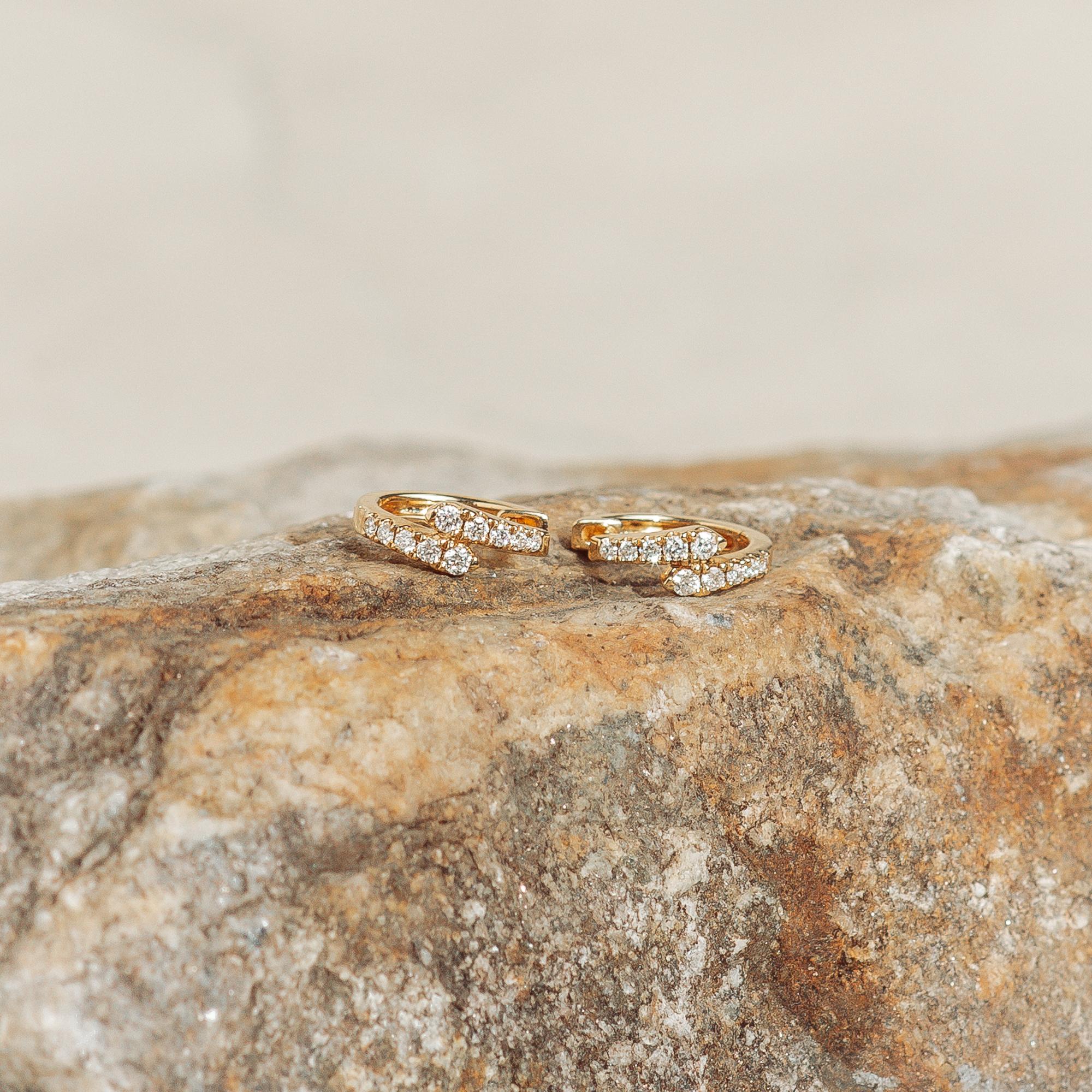 Une paire spéciale de boucles d'oreilles en diamant avec un design attrayant qui se chevauche. Ces beautés sont fabriquées en or jaune massif 18 carats et ont une forme légèrement ovale. Les diamants ont une valeur de 0,20 ctw. Les boucles