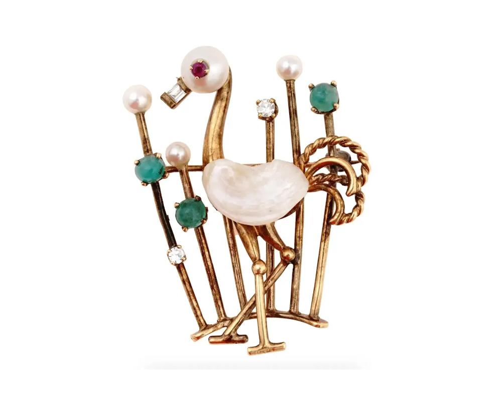A vintage 18K yellow gold figural pin brooch representing a flamingo. The piece is garnished with round and baroque natural pearls, emerald cabochons, and cut diamonds. The eye of the bird is set with a ruby stone. Marked 18K on the backside. Total
