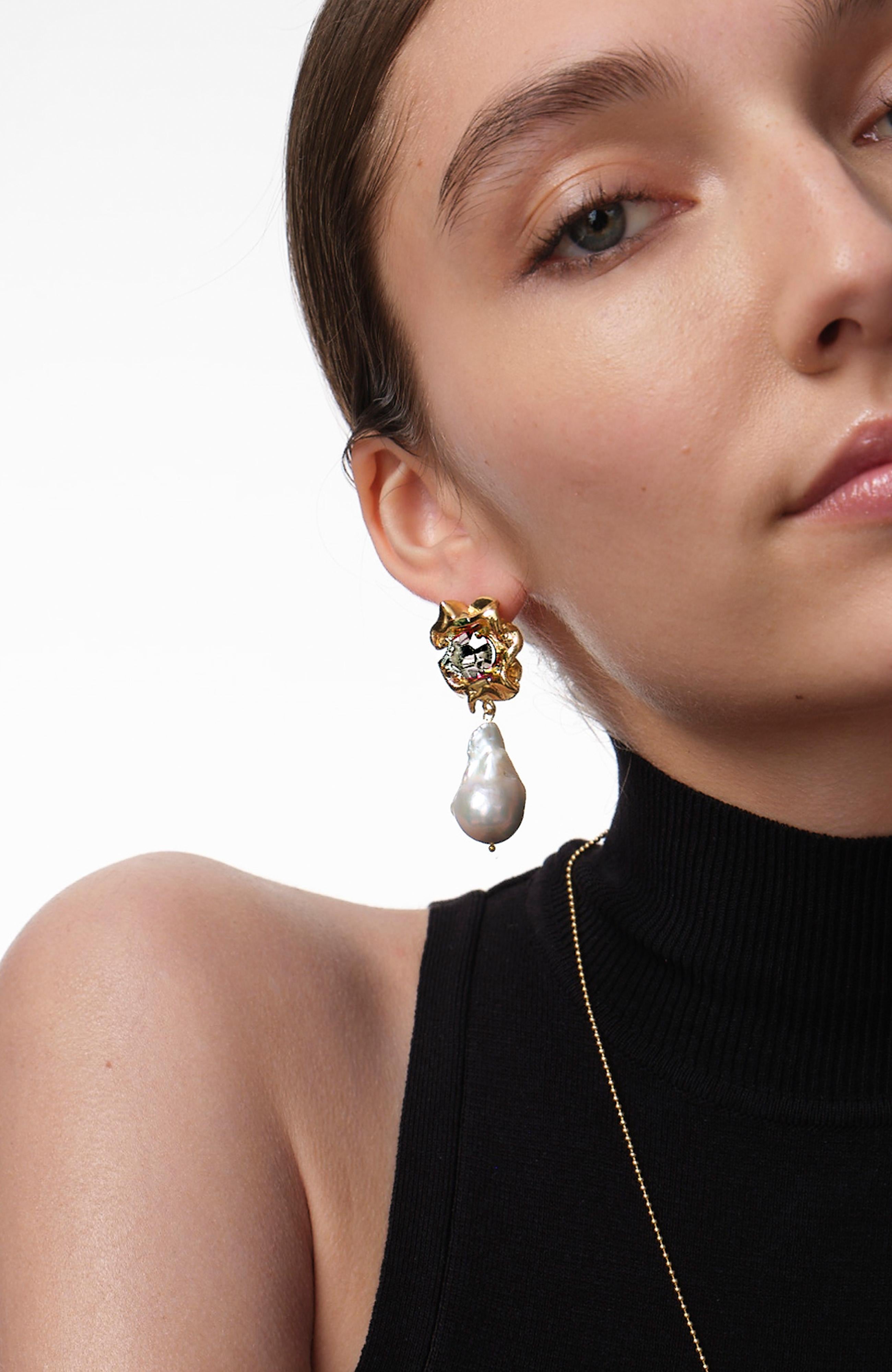 The Lola Pearl Drop Earrings feature baroques pearls suspended from rose cut crystals in a ruffled gold setting. The clear crystals, white pearls, and gold settings make them easy to style with any look. 

These earrings are both classic and modern–