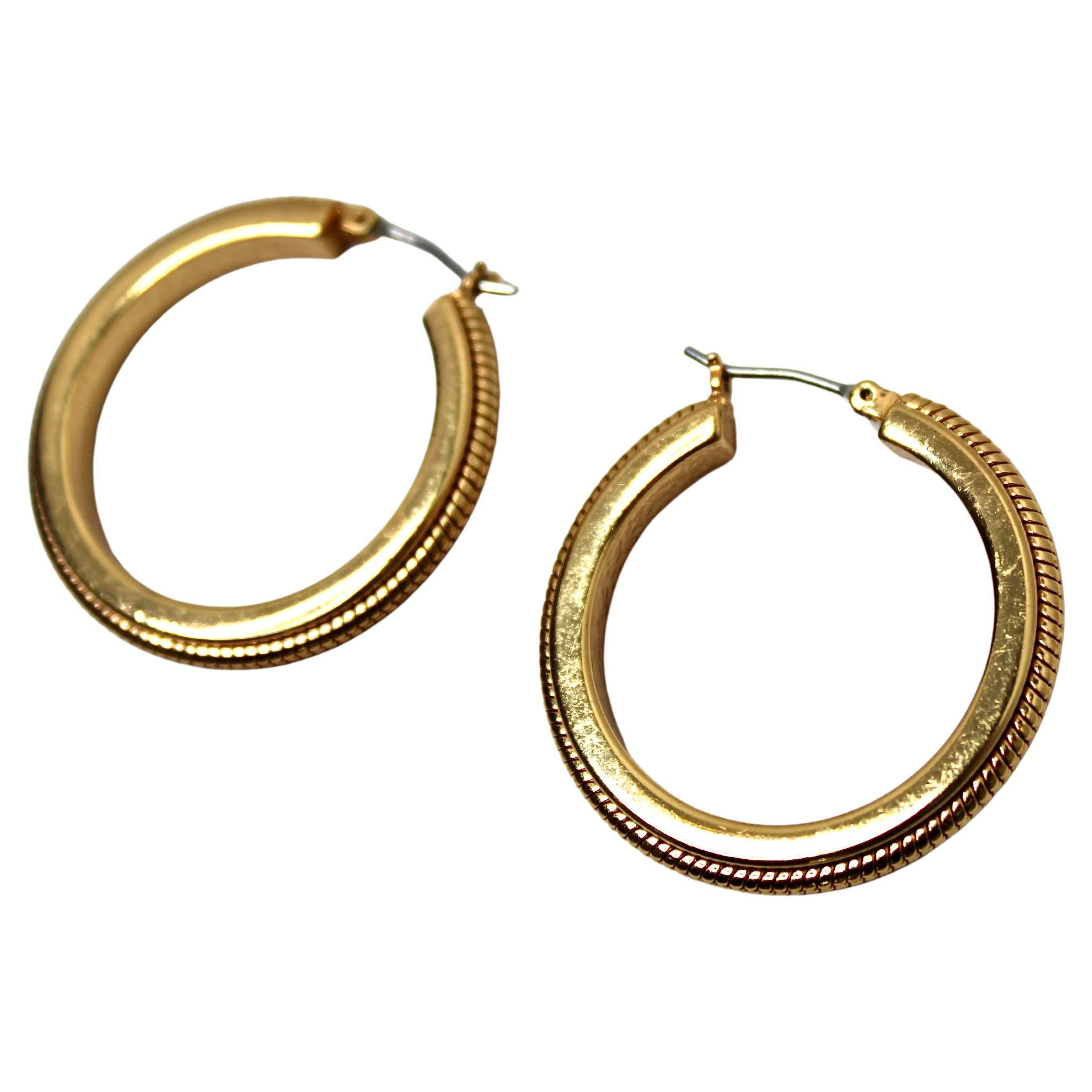 Questi splendidi orecchini a cerchio risalenti agli anni '70 circa sono un mix perfetto di eleganza vintage e stile senza tempo. Realizzati con placcatura in oro 18 carati, emanano una luce calda e lussuosa che cattura l'essenza della moda glamour