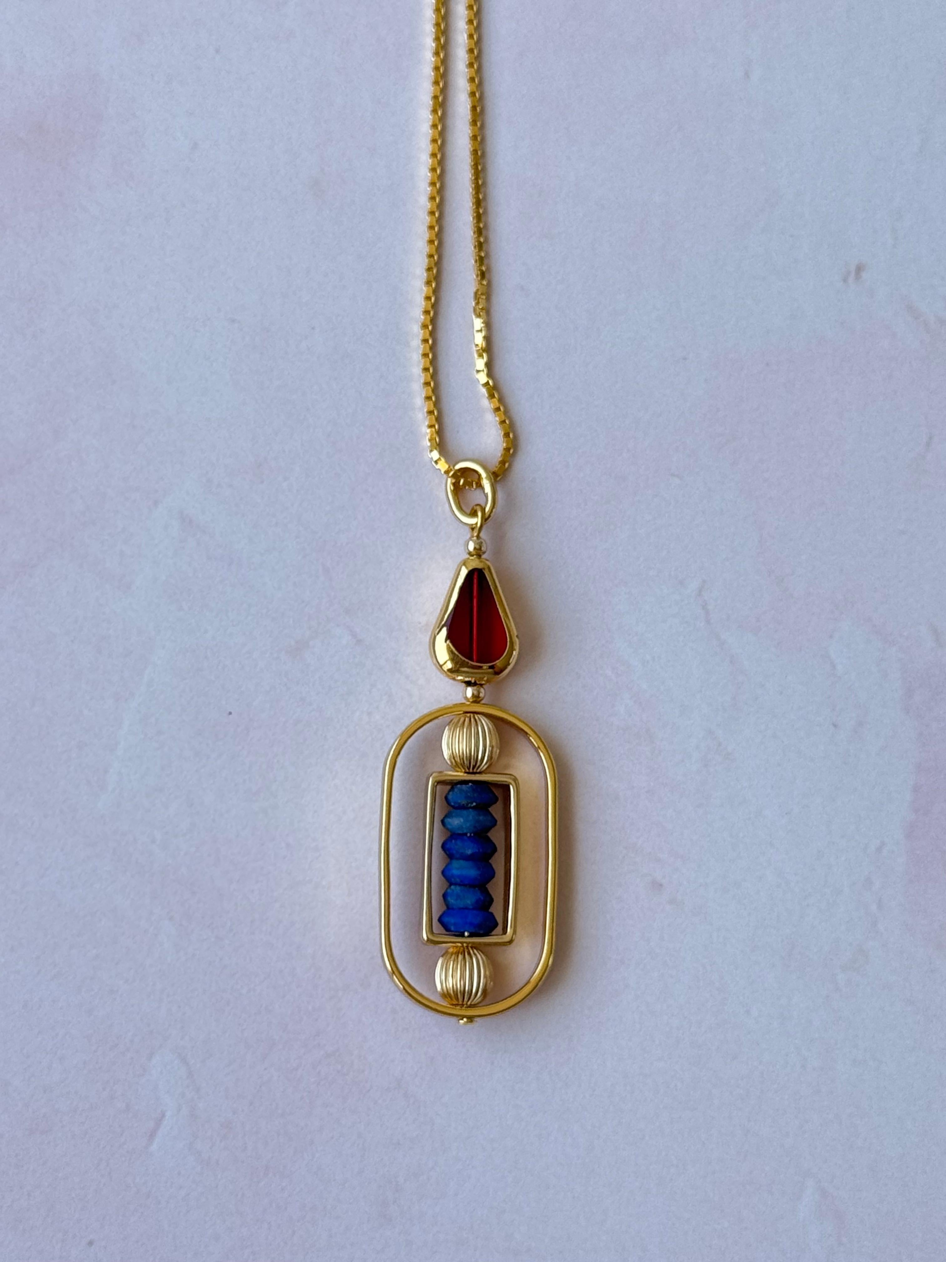 Model wear an 18 inch chain. The pendant consists of a Lapis Lazuli gemstones and green new old stock vintage German glass beads that are framed with 24K gold. Most of the beads used in the collection were hand-pressed during the 1950s-1960s. No two