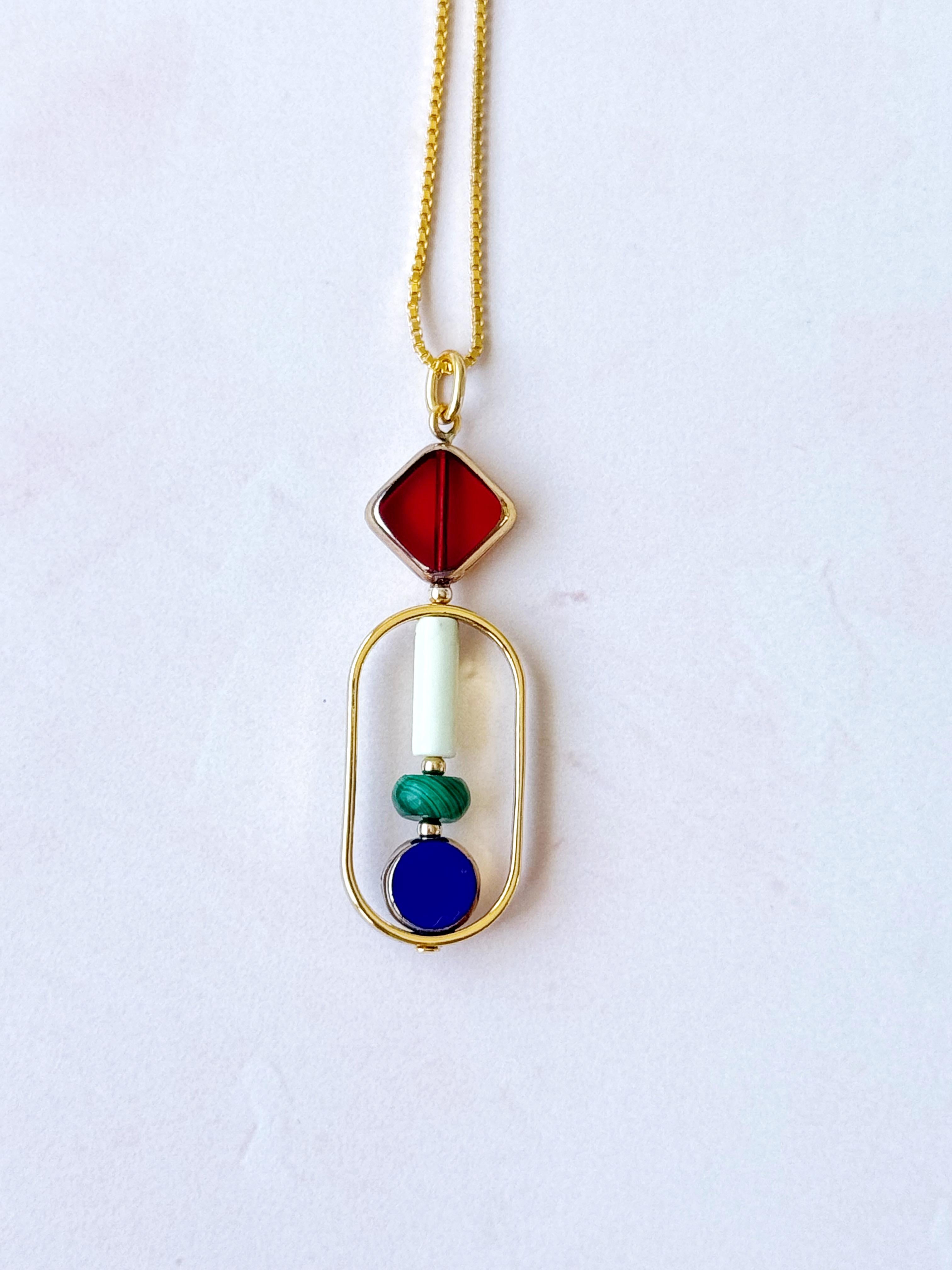 La modella indossa una catena da 18 pollici. Il ciondolo è composto da gemme di malachite e howlite e da perle di vetro tedesco vintage rosso e blu, incorniciate da oro 24 carati. La maggior parte delle perline utilizzate nella collezione sono state