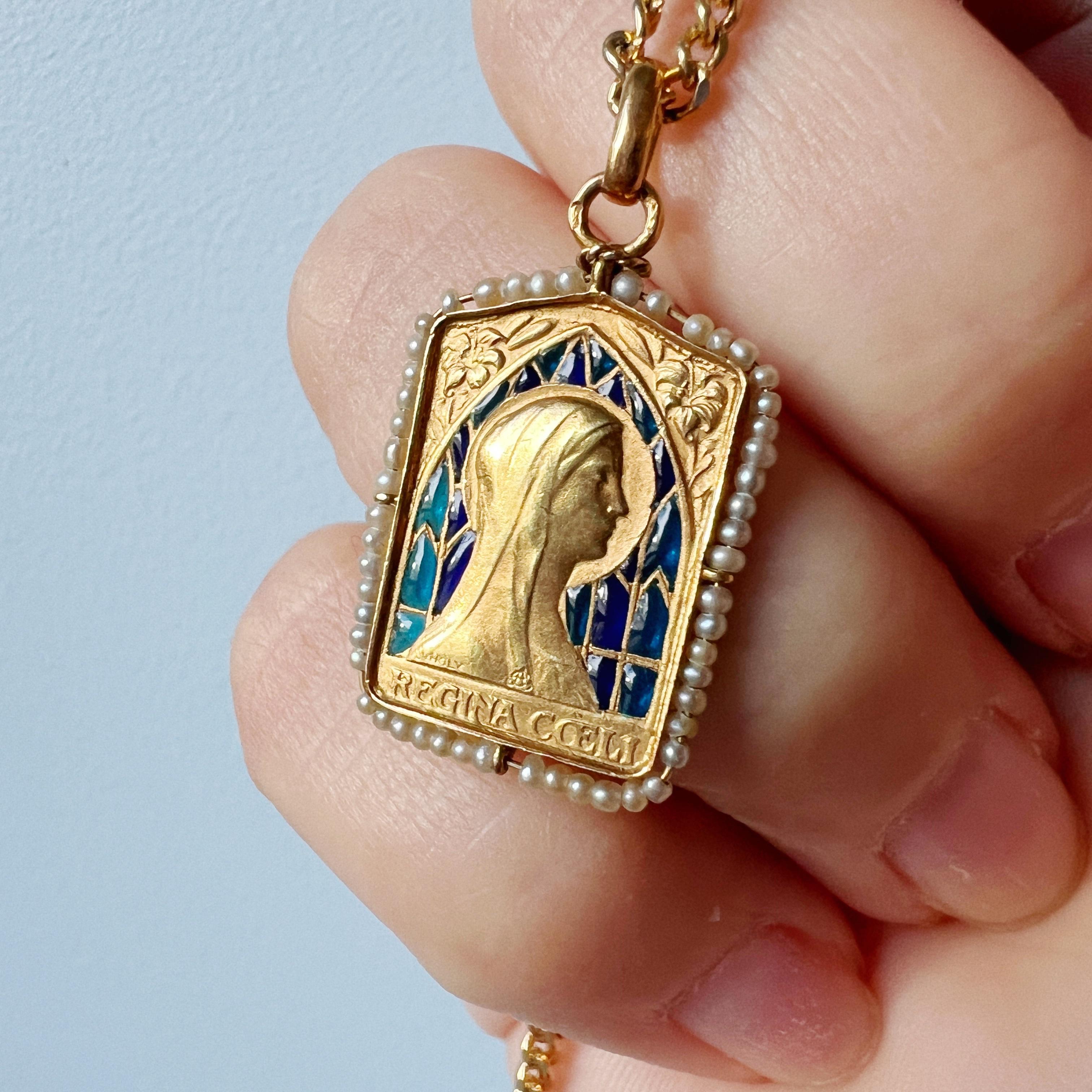 For sale an antique 18K gold medal featuring Mary, backed on a beautiful plique à jour enamel.

The plique à jour enamel adorning the medal showcases a captivating play of deep and light, two-toned blue hues. This delicate enamel is meticulously