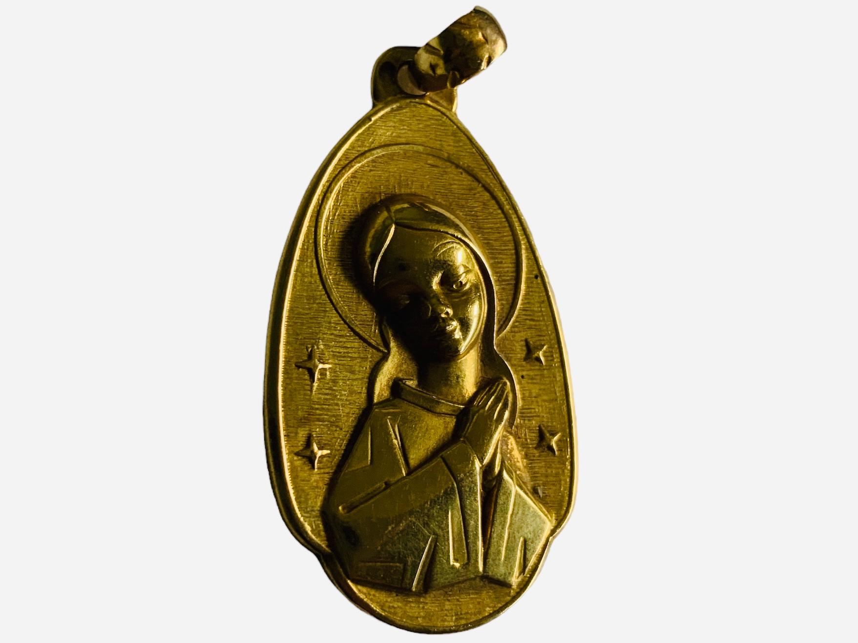 Questo è un ciondolo religioso in oro 18 carati. Raffigura una Vergine in preghiera. È montato in un ciondolo a forma di goccia in oro giallo.