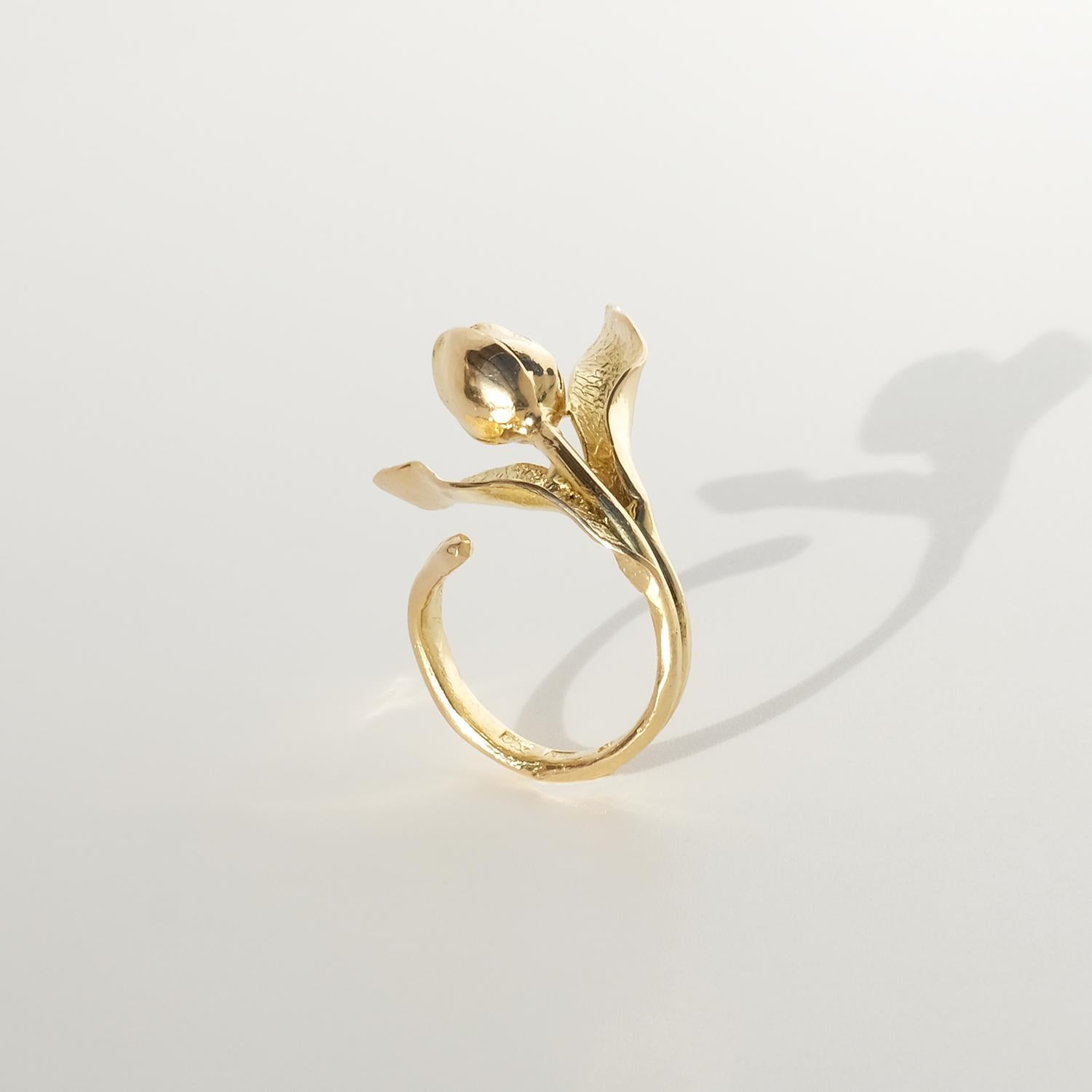 Dieser Ring aus 18 Karat Gold hat die Form einer Tulpe und ein offenes Design, das sich anmutig um den Finger legt. Das Band bildet einen zarten, fließenden Stiel, der in strukturierten Blättern und einer polierten Knospe endet und die für den