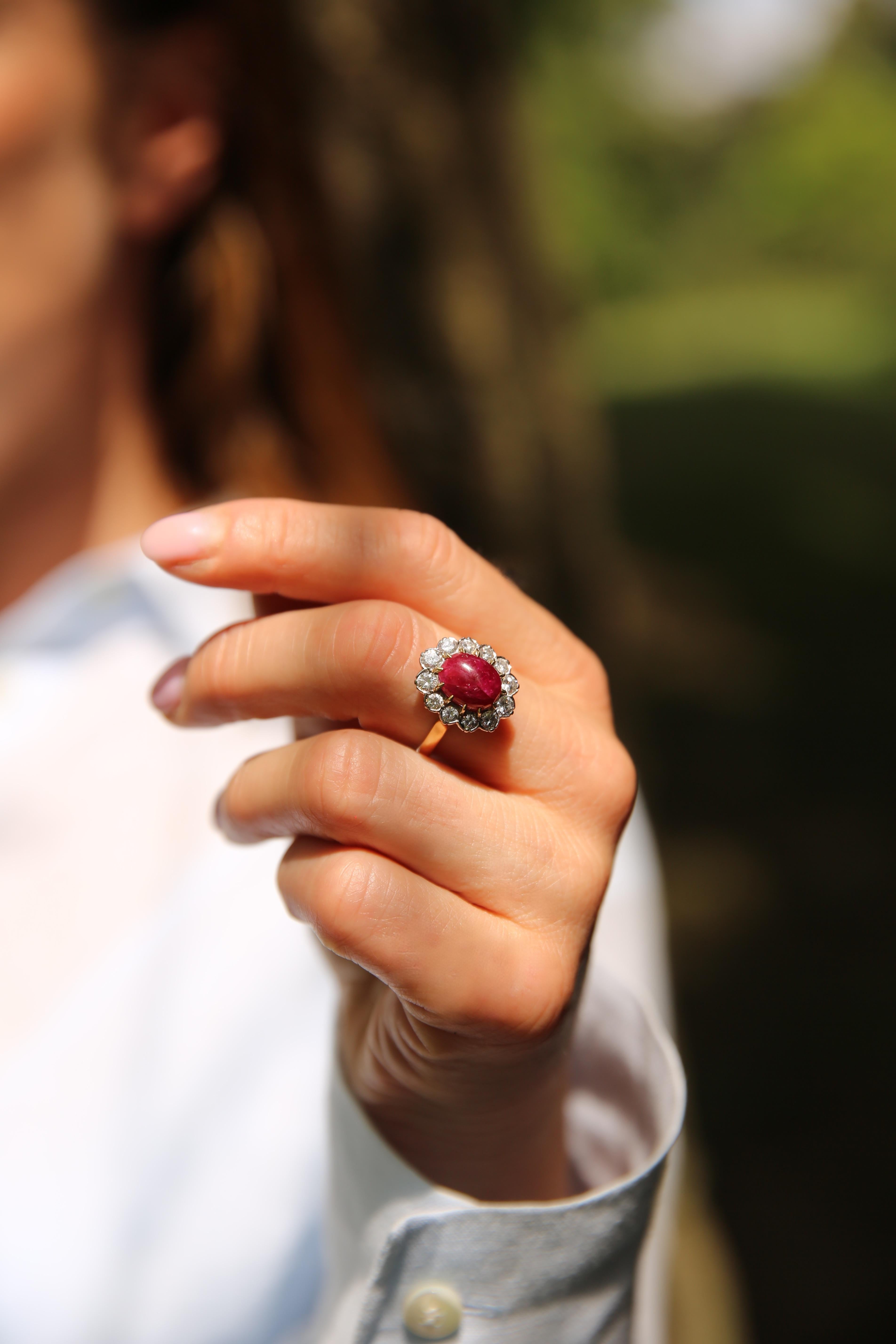 Cette bague élégante et attrayante en or jaune et blanc 18 carats est ornée d'un rubis naturel ovale richement coloré, taillé en cabochon, pesant environ 5,25 carats. Le rubis présente une teinte rouge profonde et vibrante, avec des caractéristiques
