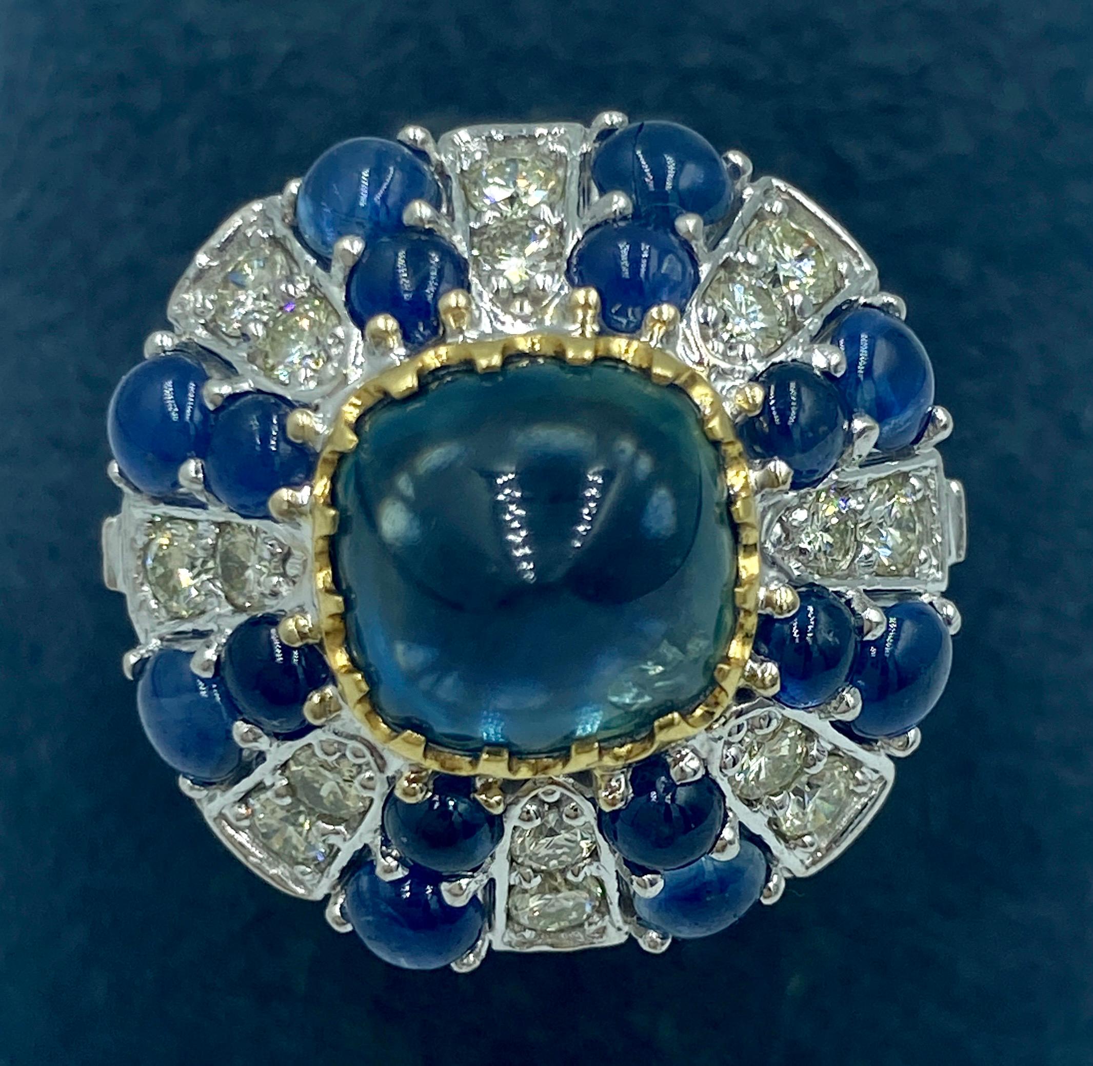 This 1950s European 18k gold cocktail ring features a central no heat sugarloaf cabochon sapphire which weighs approximately 3.5 carats and approximately 1 carat of diamonds. The smaller sapphires which adorn the ring weigh approximately 2 carats.