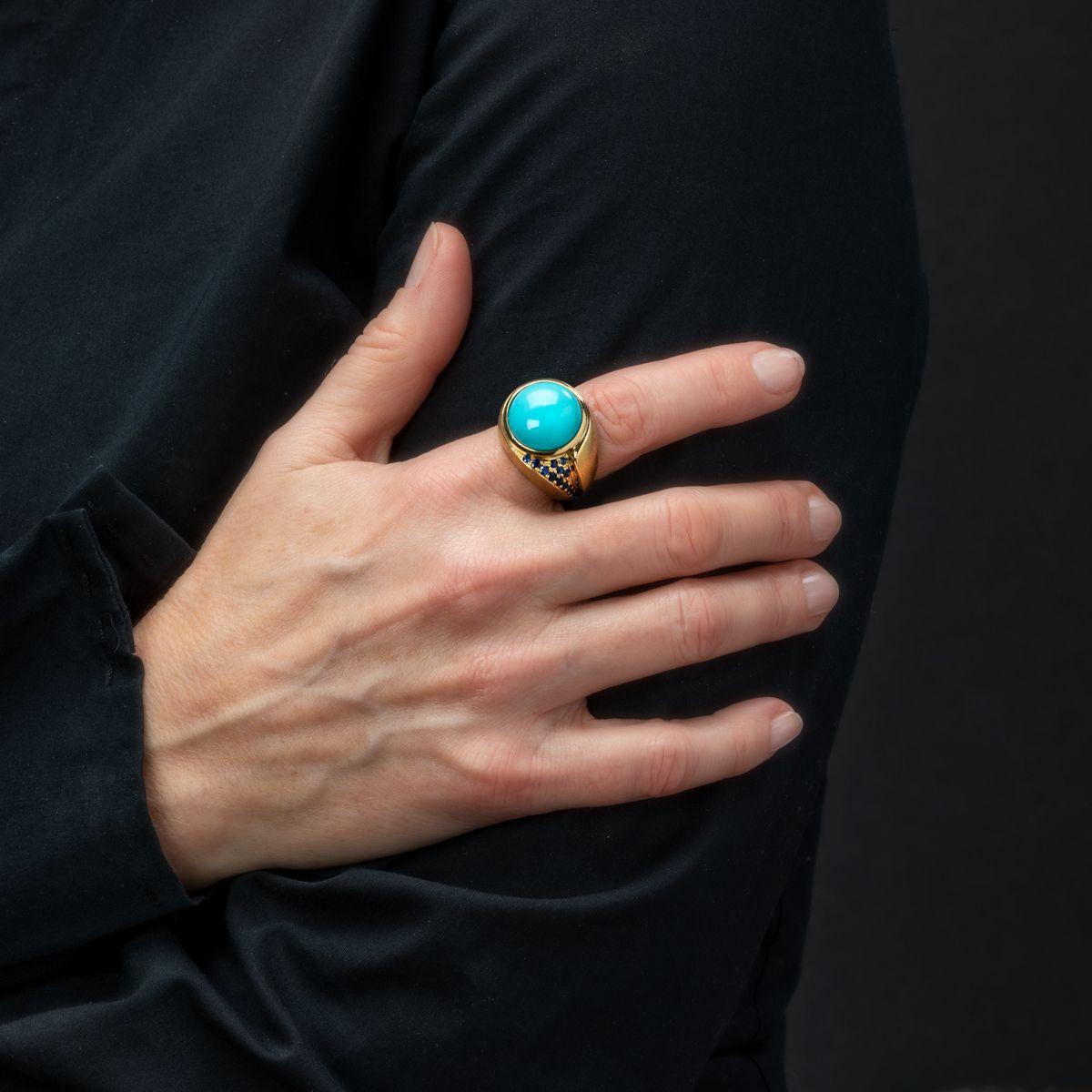 Boasting a magnificently large turquoise stone bezel set in an 18k yellow gold setting beside a wave of blue sapphires, this modern styled ring is both colourful and a fun statement piece to wear for any occasion.

Weight: Turquoise - 10.75