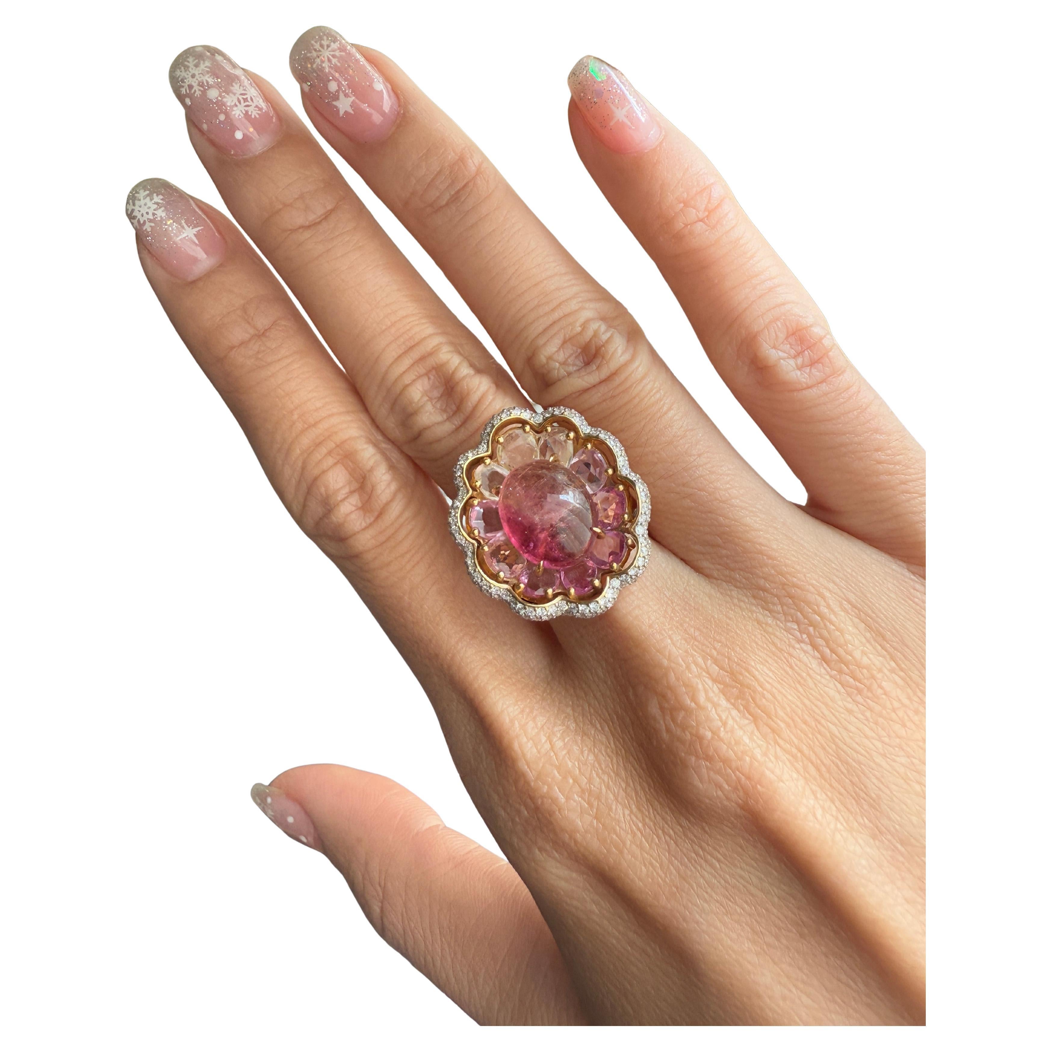 Immergiti nell'accattivante bellezza di questo anello firmato VOTIVE, dove un vibrante cabochon di tormalina rosa è al centro della scena. Abbracciato da una splendida serie di zaffiri sfaccettati e di forma irregolare dalle incantevoli sfumature