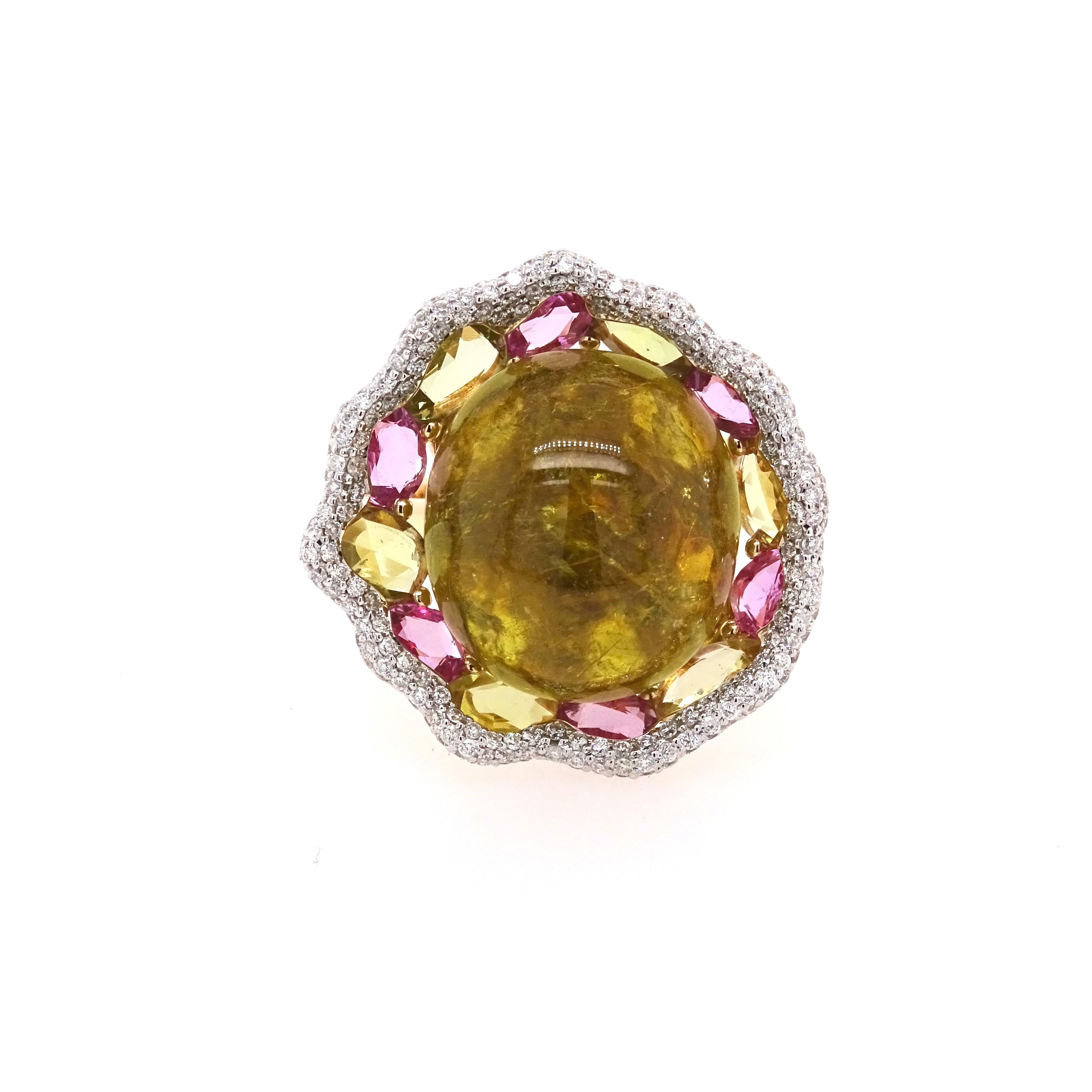 Immerse yourself in the captivating beauty of this designer ring by VOTIVE, where a vibrant yellow/green tourmaline cabochon takes center stage. Embraced by a stunning array of faceted, unevenly shaped sapphires in enchanting green and pink hues,