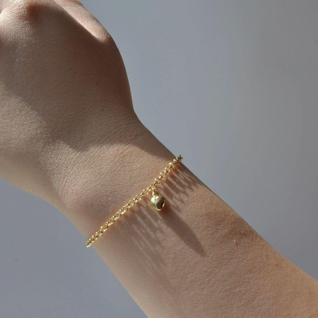 Delicato e senza tempo, questo braccialetto a catena rolo in oro giallo 18 carati è l'epitome della sobria eleganza. Caratterizzato da un piccolo charm a forma di cuore che aggiunge un tocco di romanticismo, questo pezzo è progettato per essere