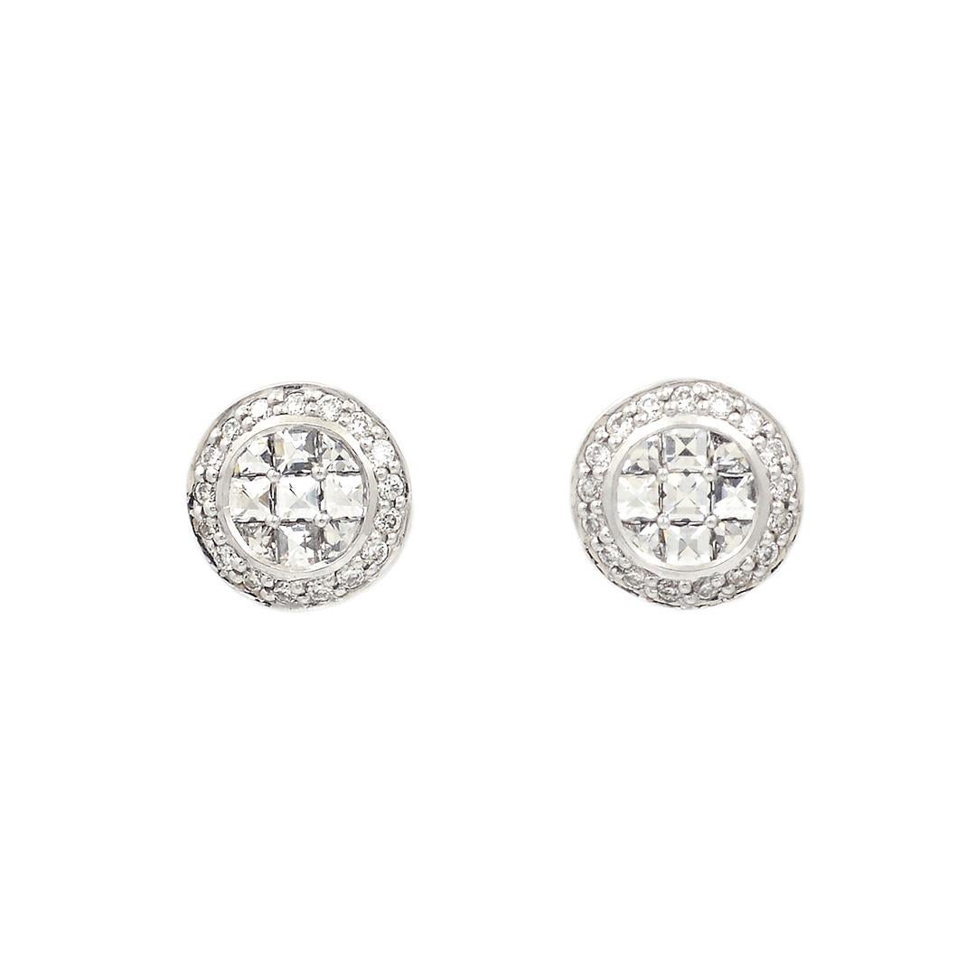 This pair of 18 karat white gold stud earrings feature a 3x3 grid of invisibly set blaze diamonds weighing an approximate combined 0.26 carats, surrounded by a halo of pave diamonds weighing an approximate combined 0.10 carats. The studs are 7mm in