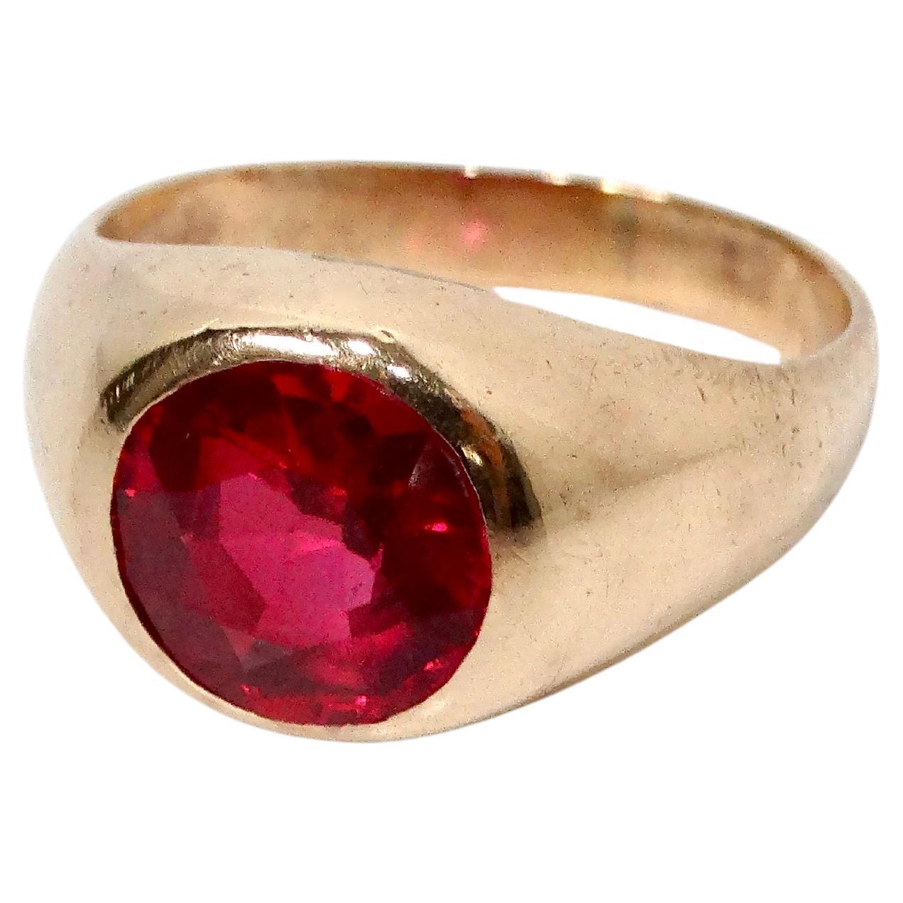 This stunning 18k Gold Round Lab Ruby Engraved Signet Ring from the circa 1970s exudes vintage charm and timeless elegance. Crafted from warm 18-karat gold, the ring features a bold, round lab-created ruby centerpiece that radiates vibrant, fiery