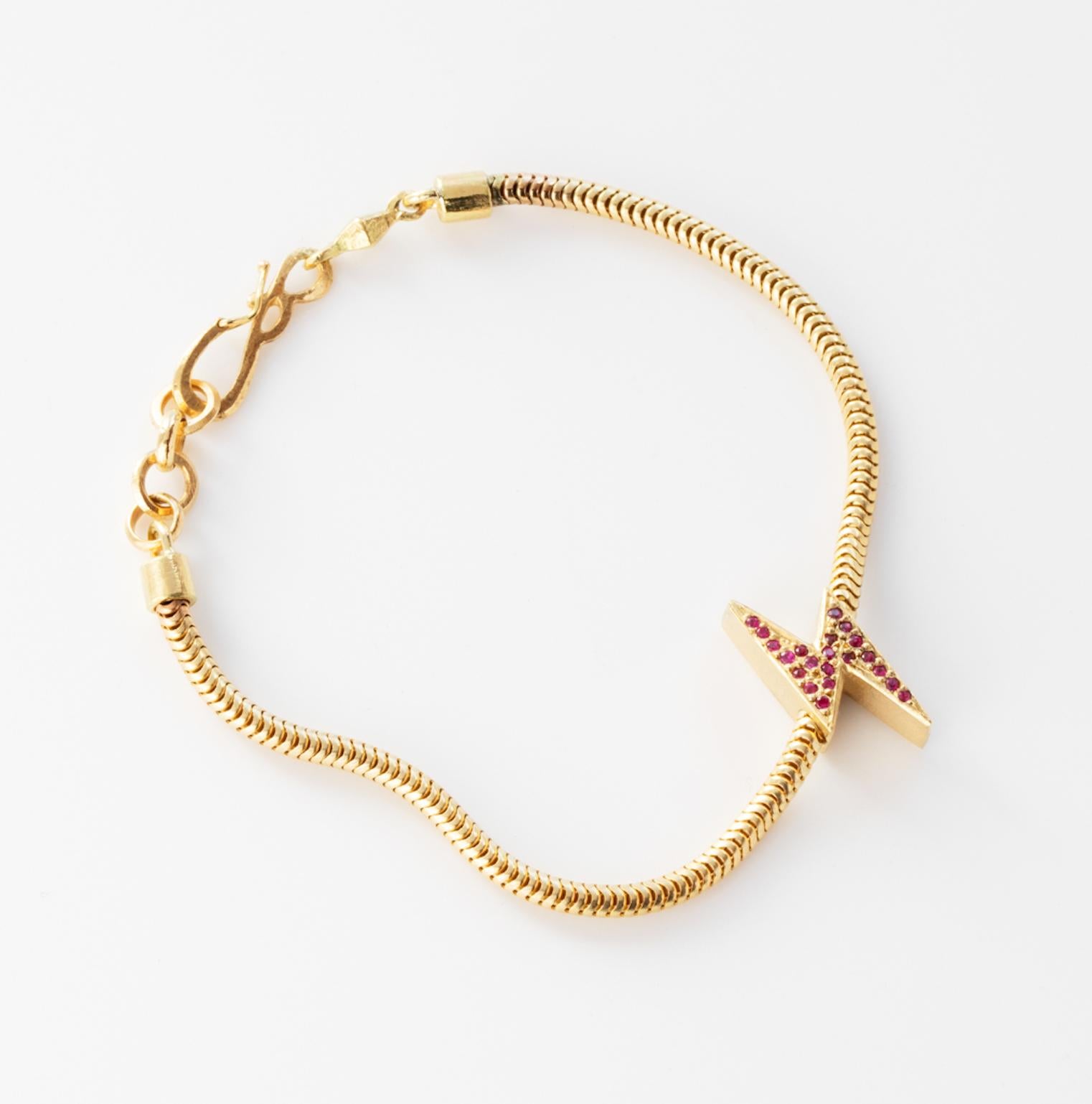 18k Yellow Gold Lightening Bolt Snake Chain Bracelet features a Ruby pave Lightening Bolt charm secured onto a solid gold snake chain bracelet, along with a clasp closure that secures the bracelet onto the wearer's wrist. 
18k Yellow Gold, Ruby Pave