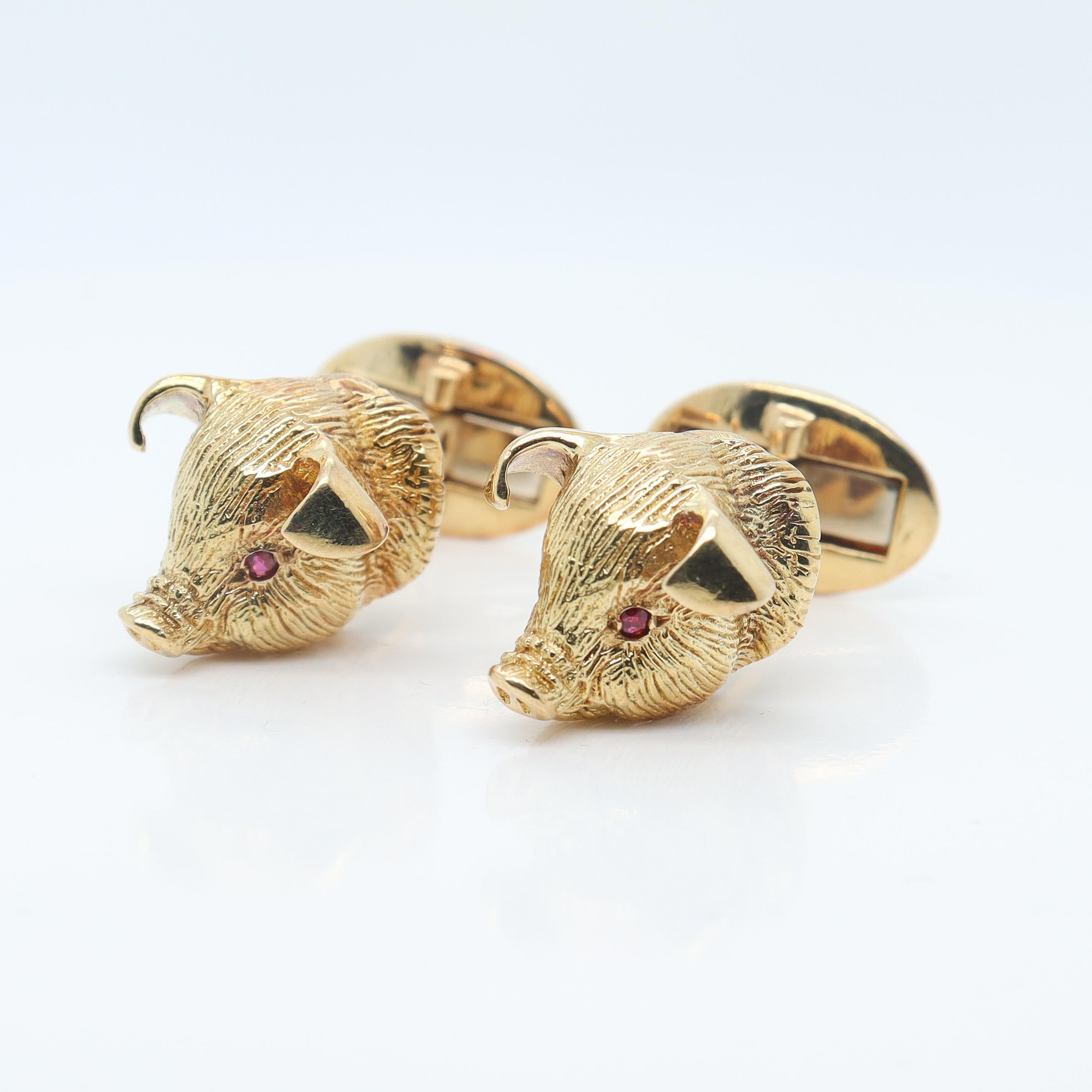 A fine pair of figural gold & ruby cufflinks.

By Craiger Drake.

In 18k gold.

Each in the shape of a pig or piglet's head.

With high polished ears, textured skin, and prong set ruby eyes.

Marked to the post 18k and with Craiger Drake's maker's