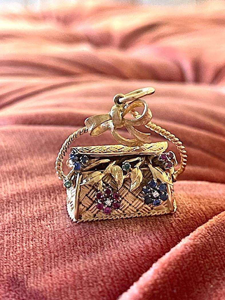 Made in Italy, this 18k solid gold charm is highly detailed with intricate leaves and stems swirling out of the top of a woven bag. Flowers crafted of diamonds, rubies, emeralds and pink and blue sapphires appear to be pouring out of this weighty
