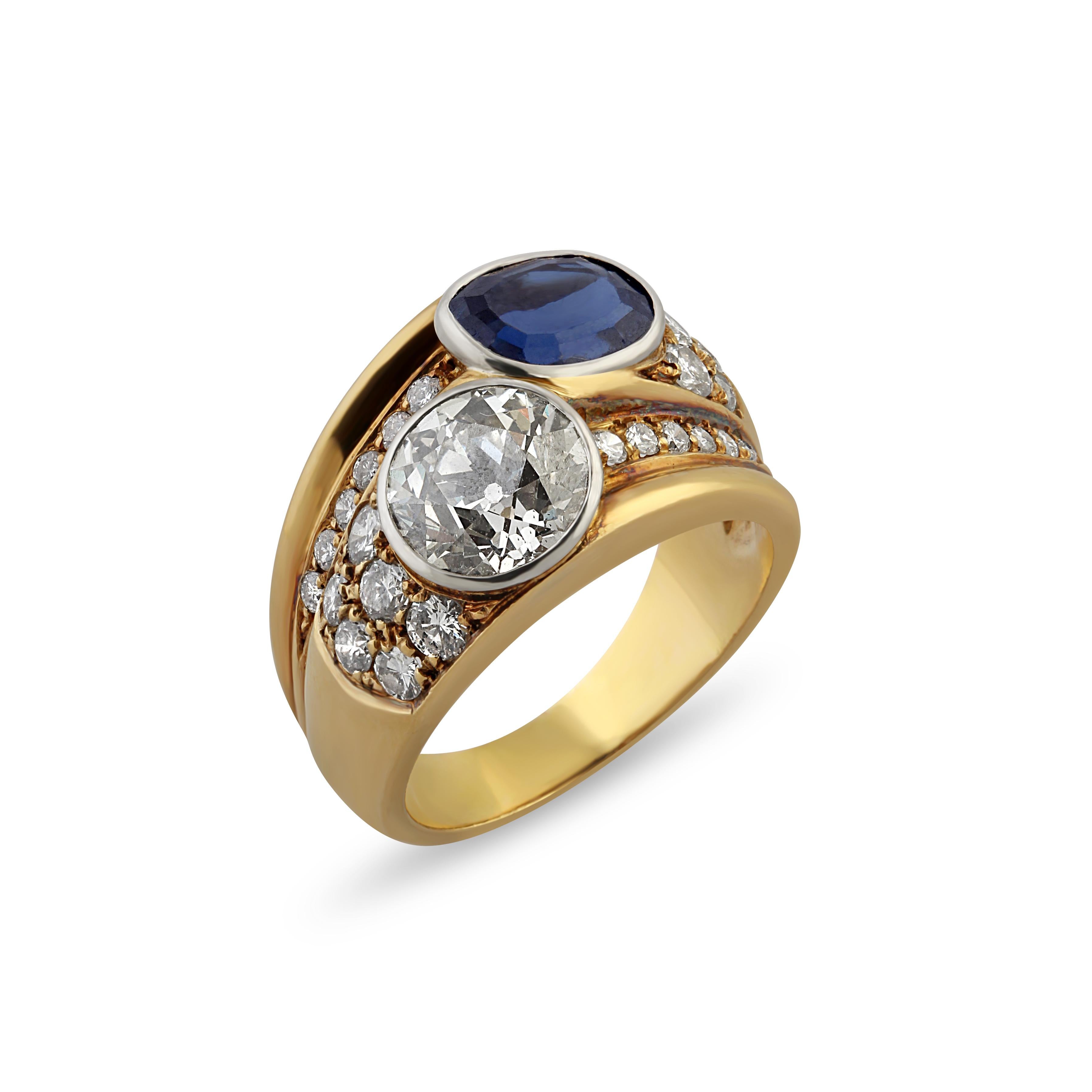 An 18k gold sapphire and diamond ring set with a round cut diamond and cushion cut sapphire surrounded by pavé set diamonds. Origin: Italy.
