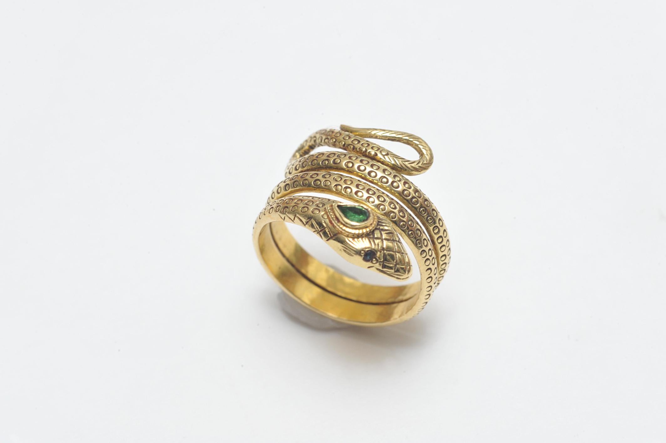 A coiled, 18K gold snake ring with hand-tooled 'scales' along the body and at the head of the snake.  Set with a faceted, pear-shaped emerald third eye and faceted blue sapphire eyes.  A size 7 as it is, but has the capacity to be reshaped.