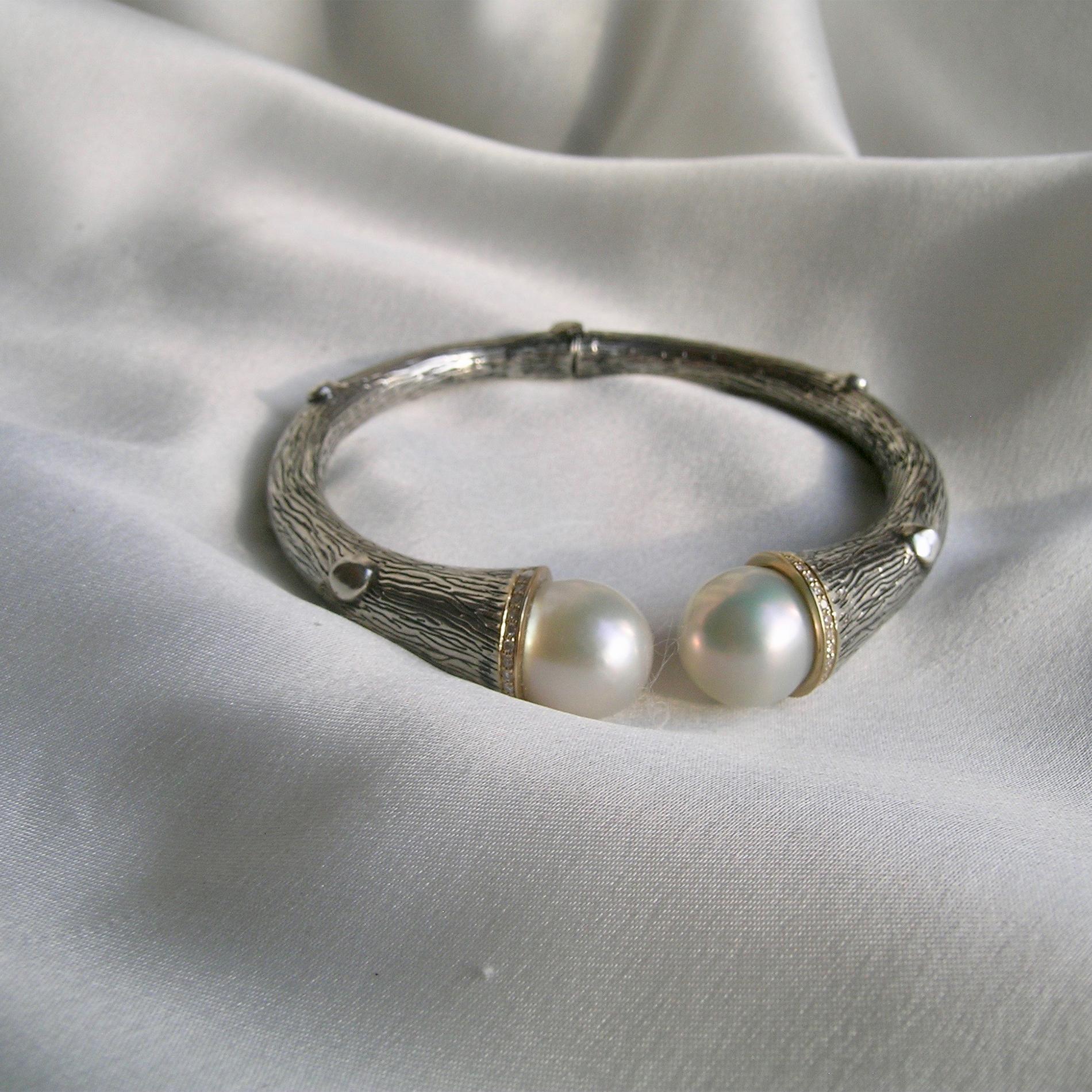 A unique version of a popular style cuff, bracelet.   The hefty, body of the piece is made of  silver and has a hinge to open.  Two very nice fresh water pearls are on the ends and set in gold with pave diamonds. (0.36cts. diamonds). What makes the