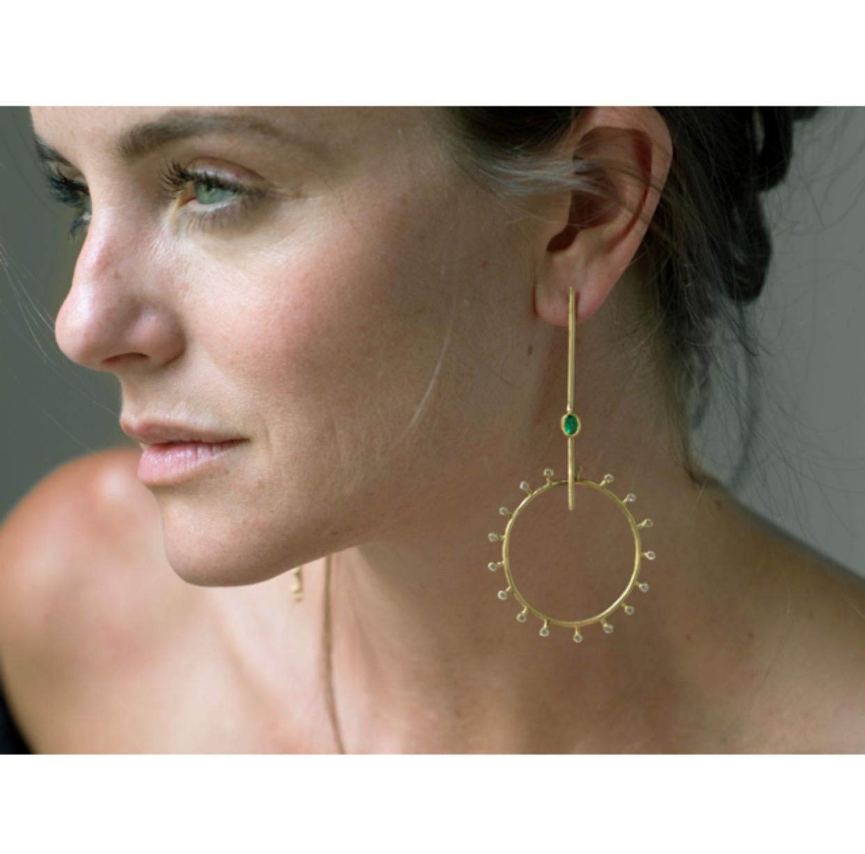 This one of a kind, playful pair of earrings feature Gemfields ethically sourced Zambian emeralds and over a carat total weight of brilliant white diamonds. A hidden hinge allows the hoop section to swing freely, allowing the diamonds to catch the