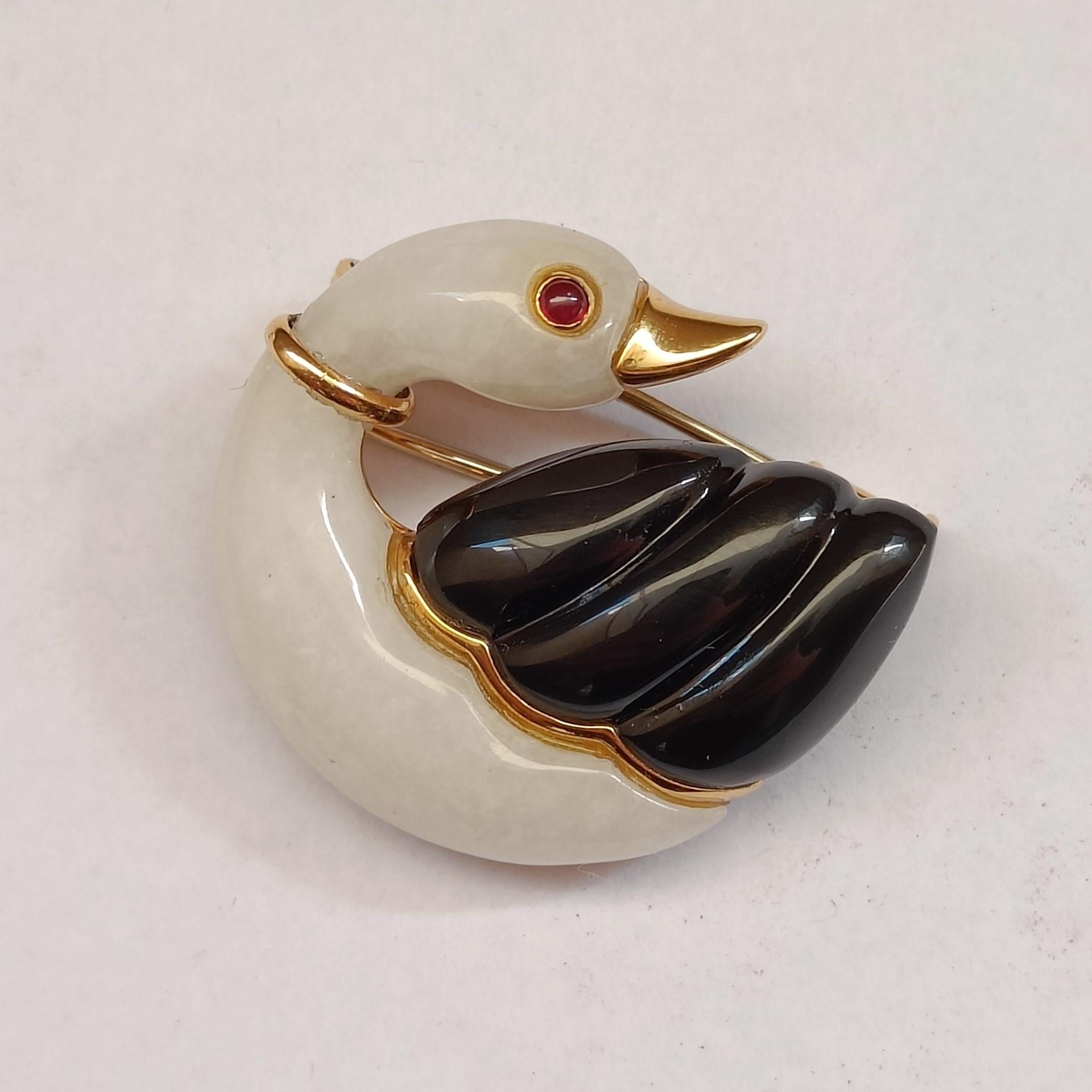An onyx, white chalcedony, ruby and 18k gold swan clip brooch.
Stamped 750. Very good condition.

Dimensions 3x3 cm (approx.)
Weight 12.5 grams
