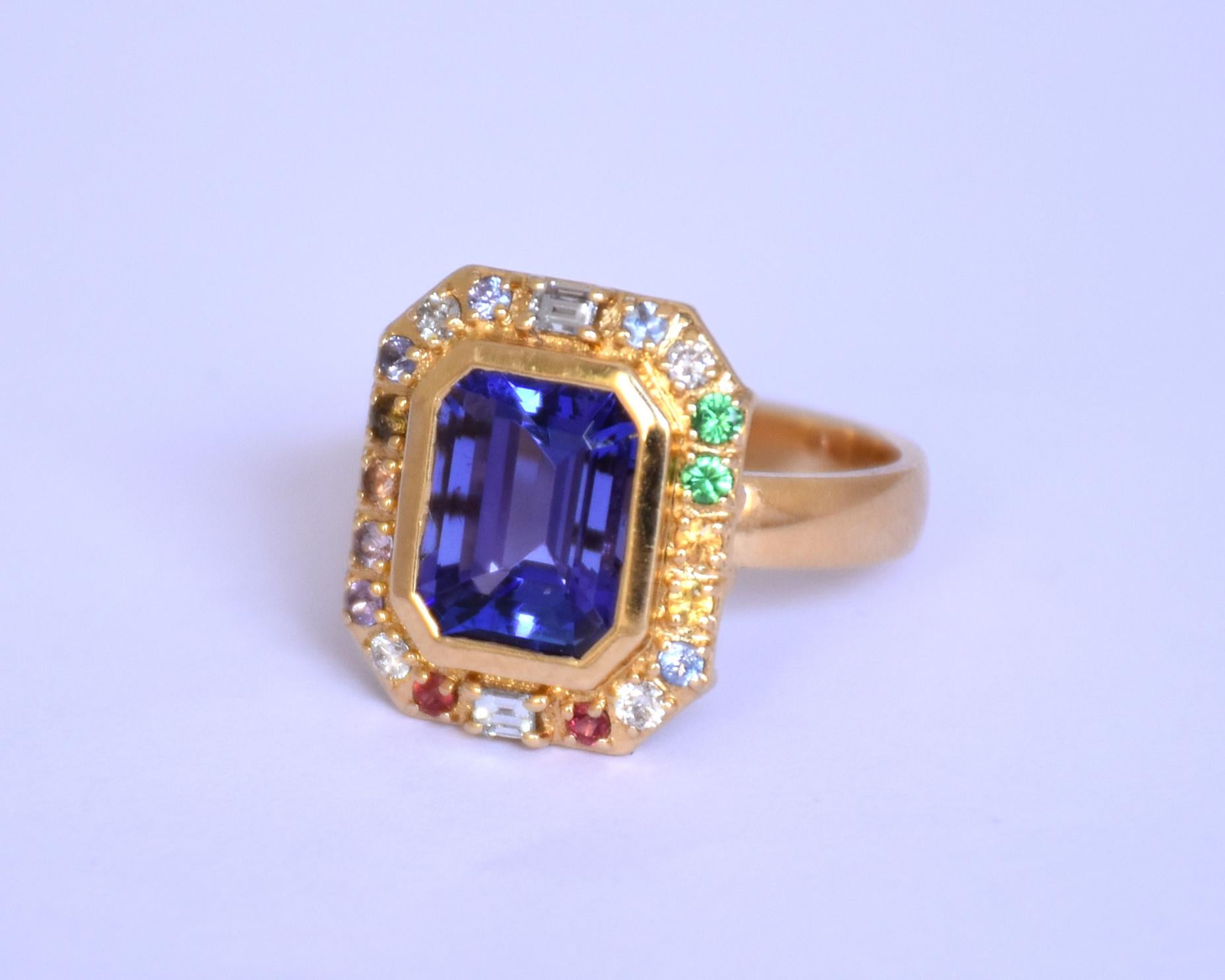 A 18K gold ring with a centre loupe clean Tanzanite surrounded with multi sapphires and diamond. 

Centre piece is an emerlad cut Tanzanite of 3.62ct and the ring has 0.35ct diamonds. The ring size can be changed as per the customer request.

This