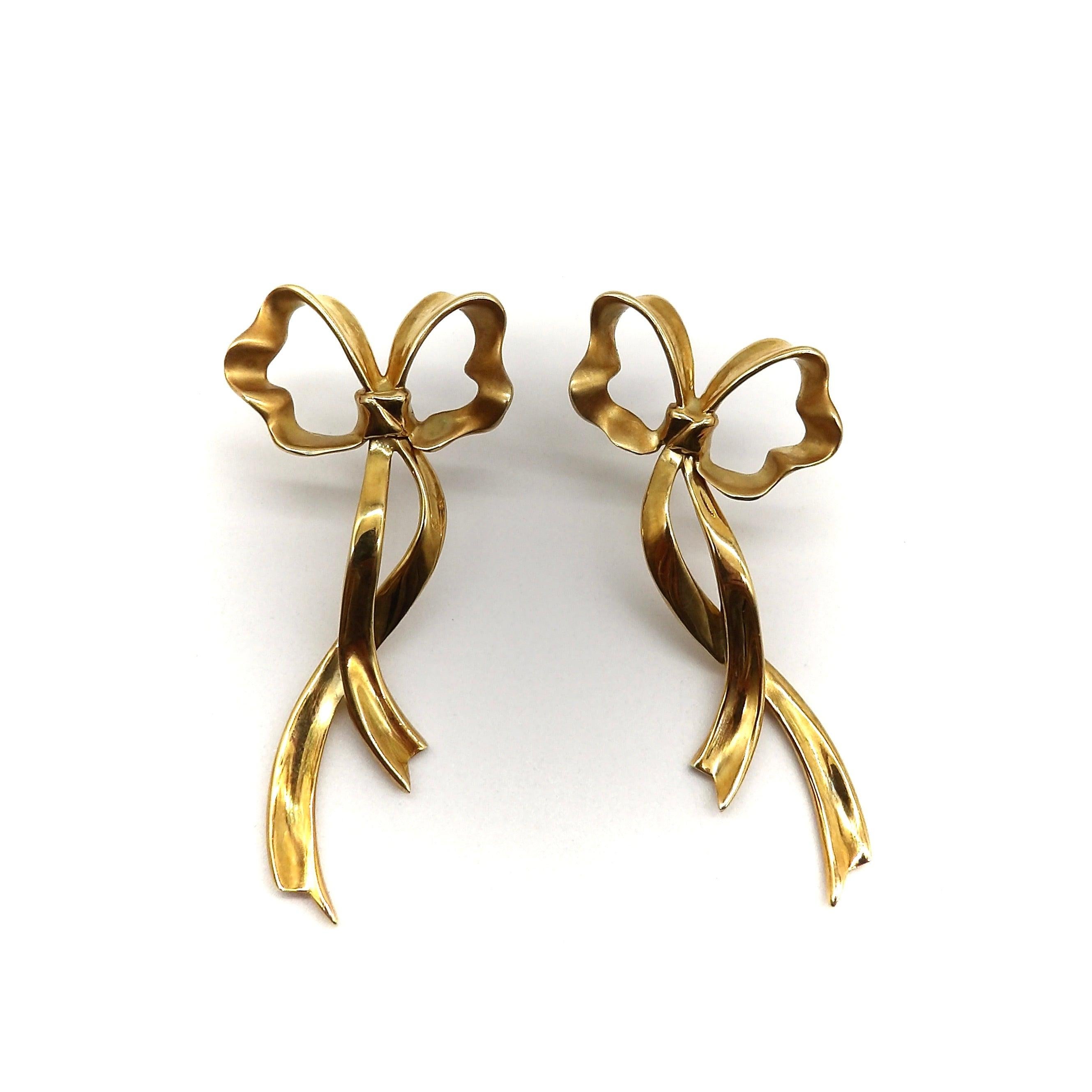 These 18k gold Tiffany & Co. earrings consist of elongated bows with dangling, flowing ribbons. Circa 1985, these bows are a bold take on a classic design, harkening back to the bows seen in retro jewelry of the 1940’s and 1950’s. They capture the