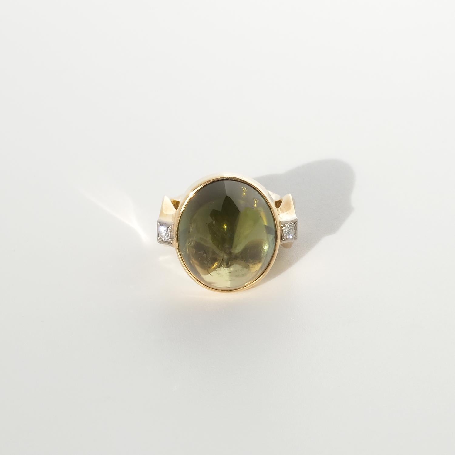 Cette bague en or 18 carats est ornée d'une étonnante tourmaline verte taillée en cabochon, d'une teinte riche et profonde. La pierre précieuse est sertie sur un anneau audacieux et sculptural aux côtés larges et anguleux qui se rétrécissent