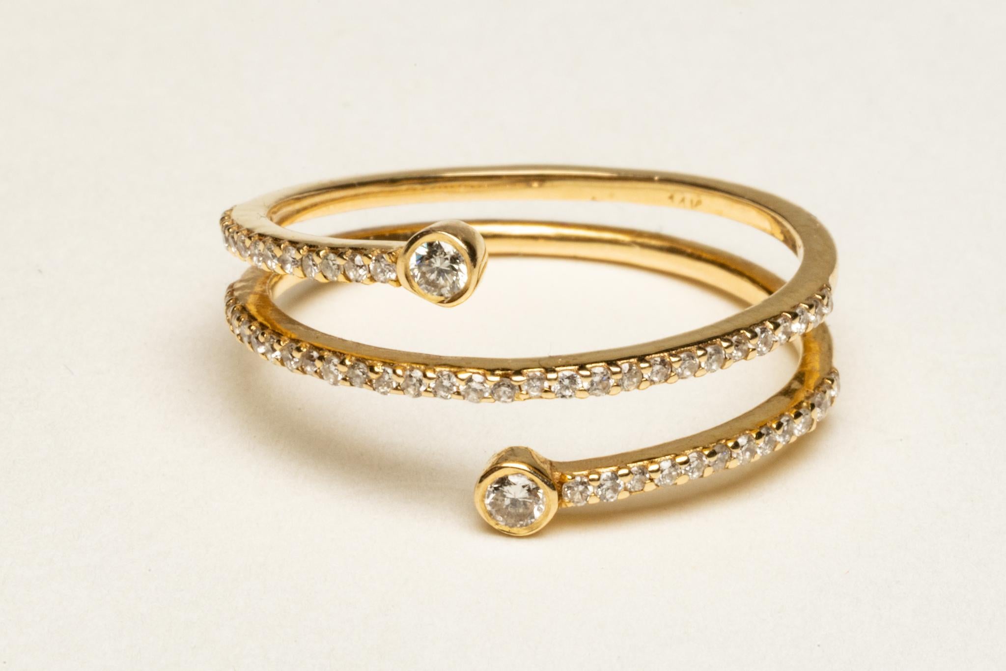 Un'elegante fascia tripla in oro 18 carati con diamanti rotondi a taglio brillante incastonati a pavé.  Ogni estremità è completata da un diamante leggermente più grande.  Il peso totale dei diamanti è di 0,30 carati.  La misura dell'anello è una 7.