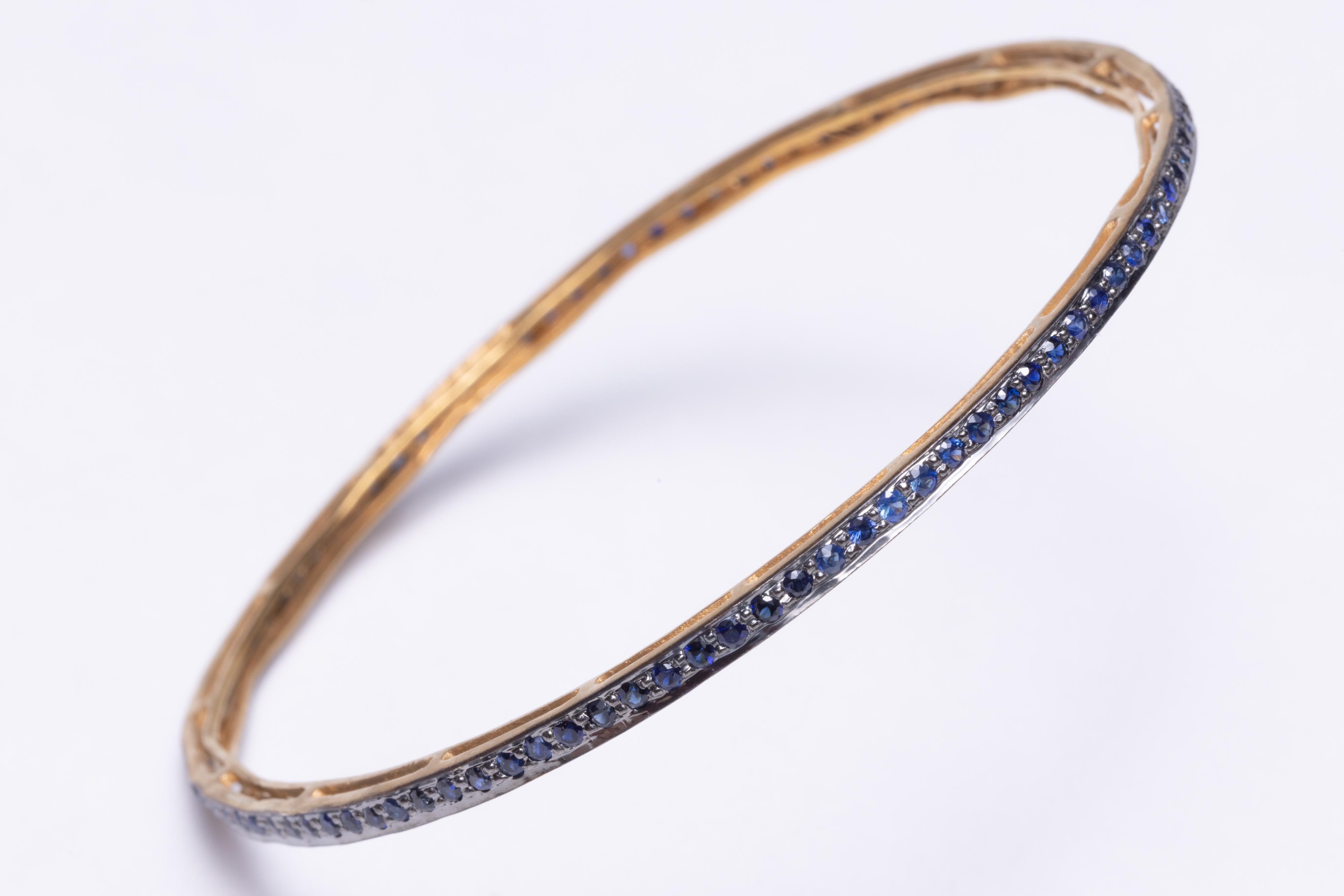 A pair of faceted, round sapphire bangles in an 18K gold setting.  Inside circumference measures 2.5