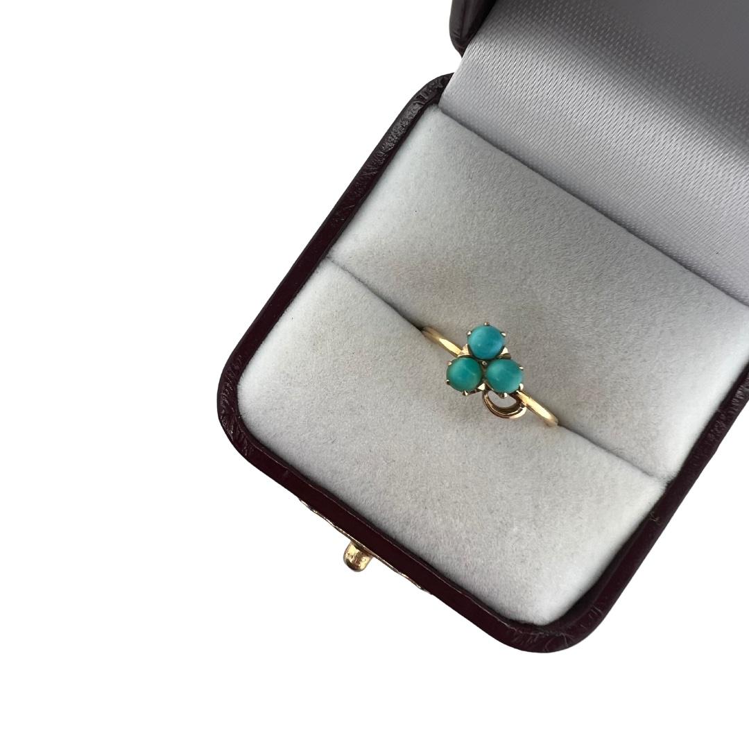 This charming antique piece was crafted sometime during the Victorian design period (1840-1900). The 18K gold setting is a classic three-stone ring with three turquoise stones ranging in color adorning the top of the shank. Due to turquoise’s porous