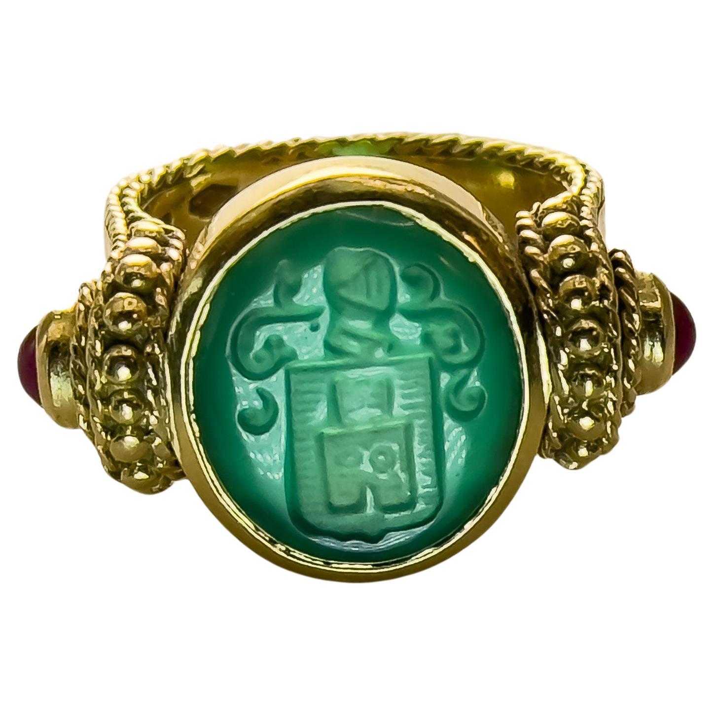 Indulge in the luxury of bygone eras with this stately vintage signet ring. Expertly crafted in 18K gold, it features an intricately carved natural jade centerpiece, flanked by two rich cabochon rubies. A substantial piece with a total weight of